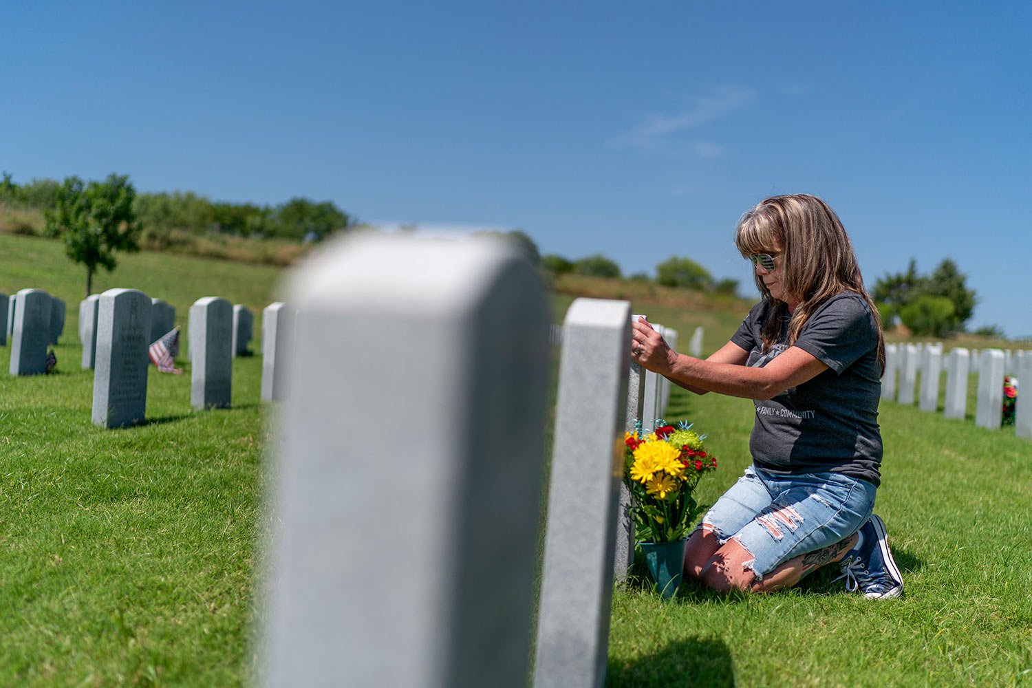  Barbie Rohde touches the tombstone of her son, Army Sgt. Cody Bowman, at the Dallas-Fort Worth National Cemetery, Sunday, June 11, 2023, in Dallas, Texas. (AP Photo/David Goldman)  