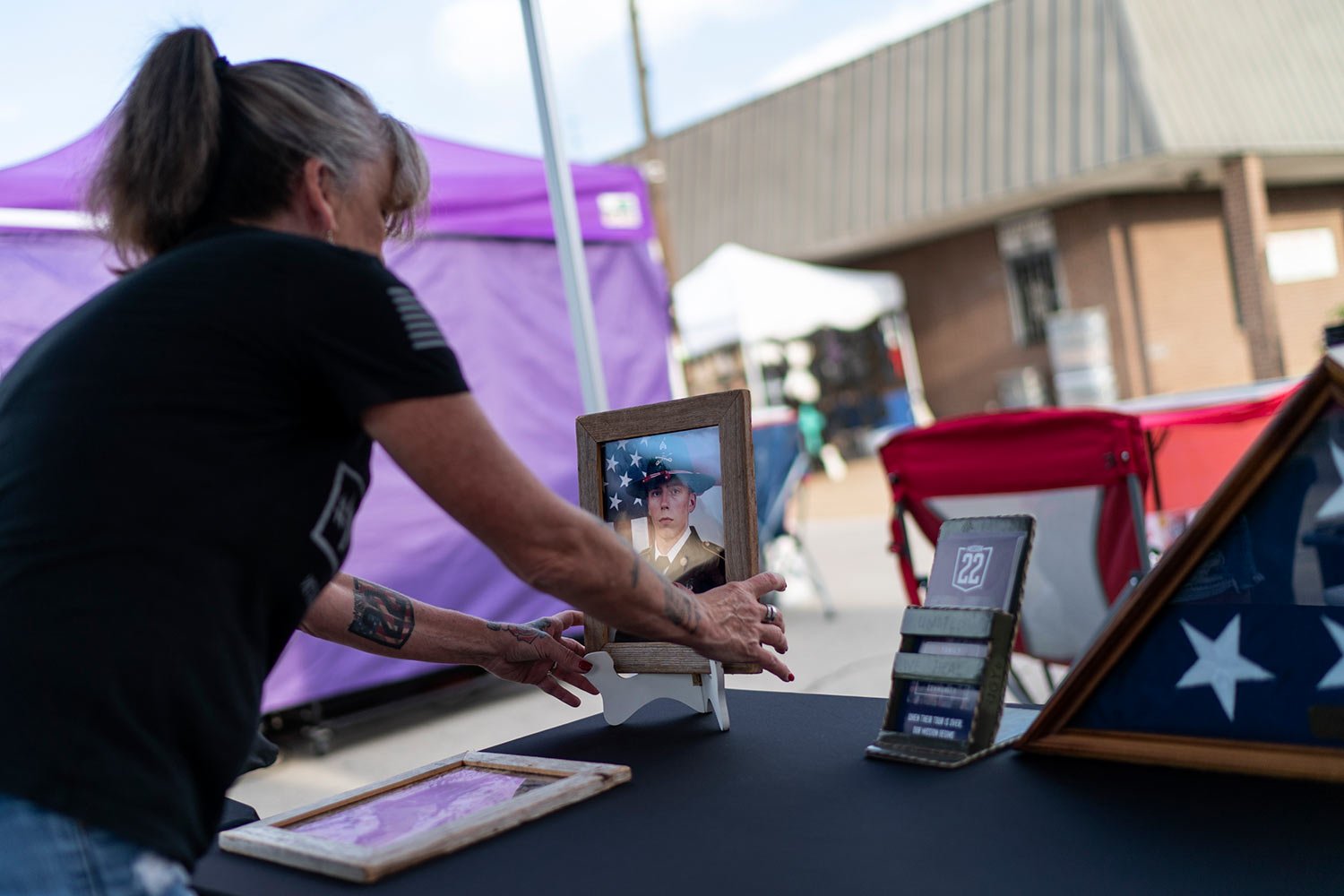  Barbie Rohde, sets up a photo of her son, Army Sgt. Cody Bowman, at a festival while volunteering for Mission-22, a nonprofit that aims to end military and veteran suicide, Saturday, June 10, 2023, in Jacksonville, Texas. (AP Photo/David Goldman)  