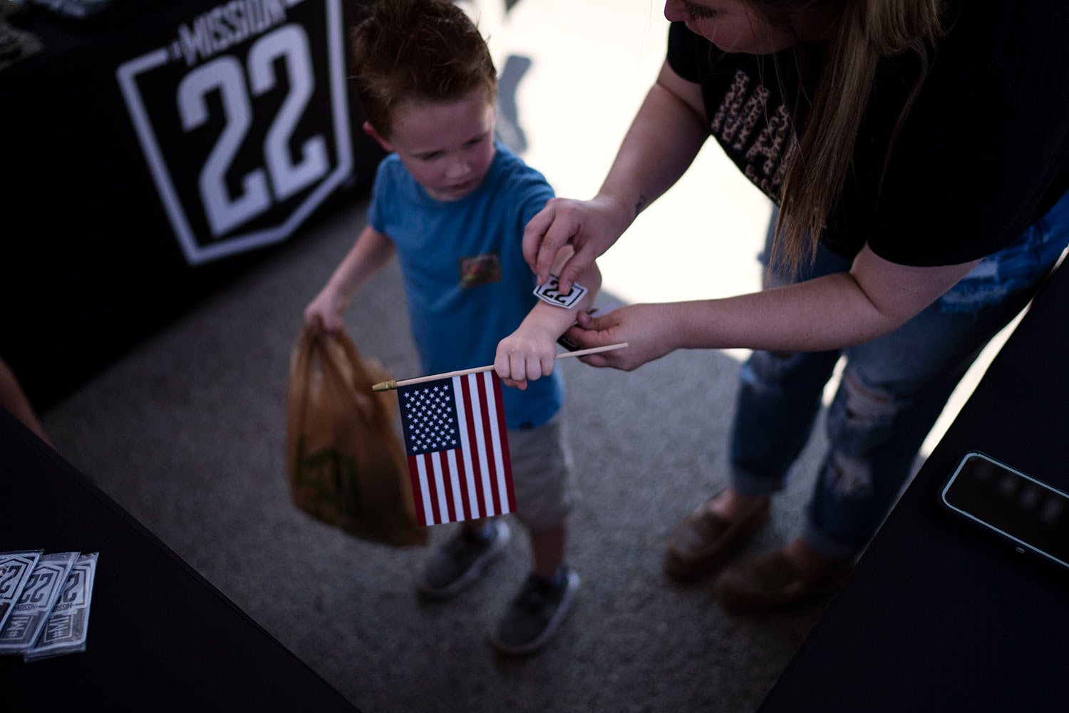  A child gets a Mission-22 sticker, a nonprofit that aims to end military and veteran suicide, Saturday, June 10, 2023, at a festival in Jacksonville, Texas. (AP Photo/David Goldman)  