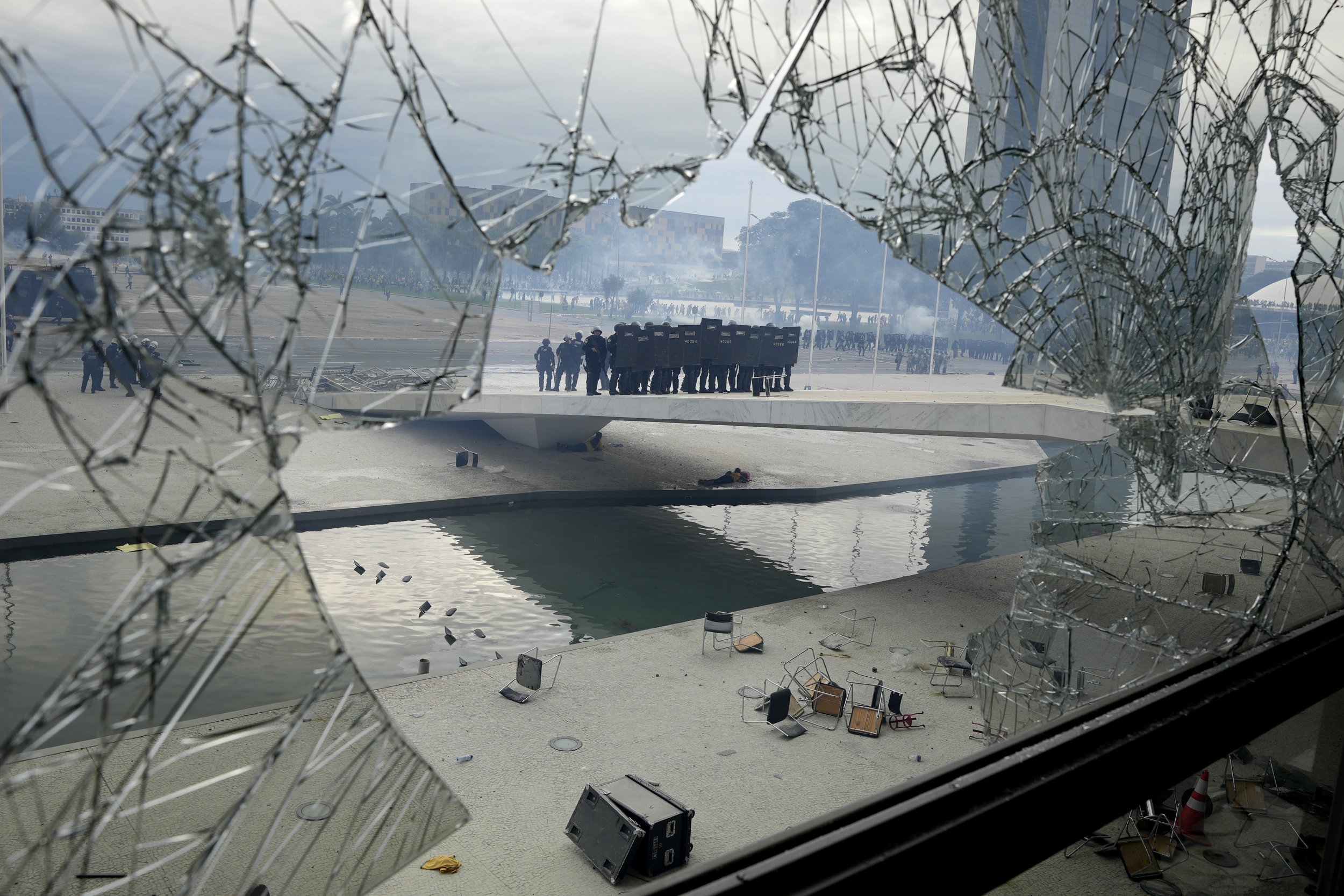  Police stand outside Planalto Palace, the official workplace of Brazil’s president in Brasilia, as seen through a shattered window after supporters of Brazil's former President Jair Bolsonaro stormed the building on Jan. 8, 2023. (AP Photo/Eraldo Pe