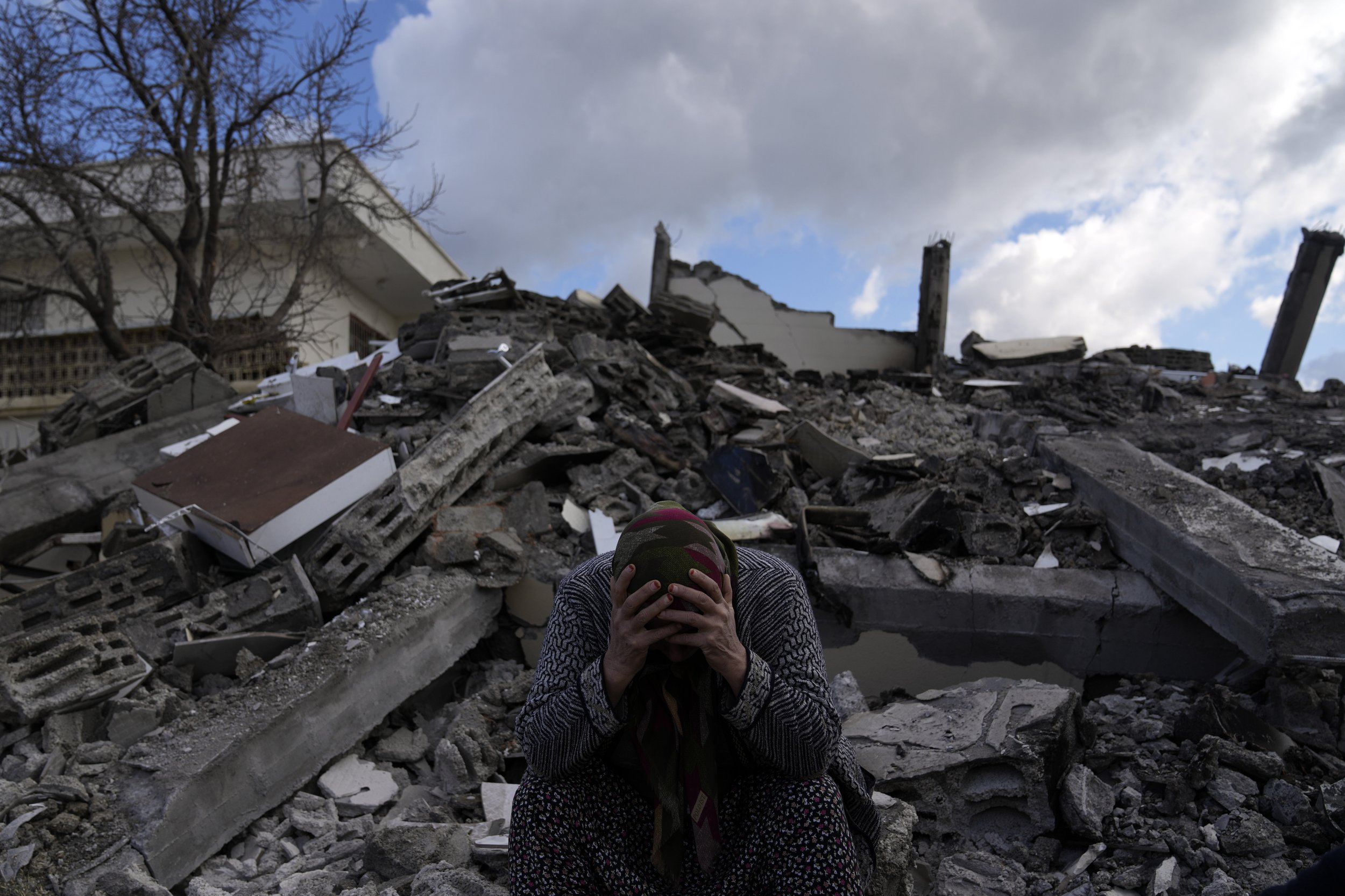  A woman sits on the rubble as emergency rescue teams search for people under the remains of destroyed buildings in Nurdagi town on the outskirts of Osmaniye, Turkey, on Feb. 7, 2023, the day after a powerful earthquake hit southeast Turkey and Syria