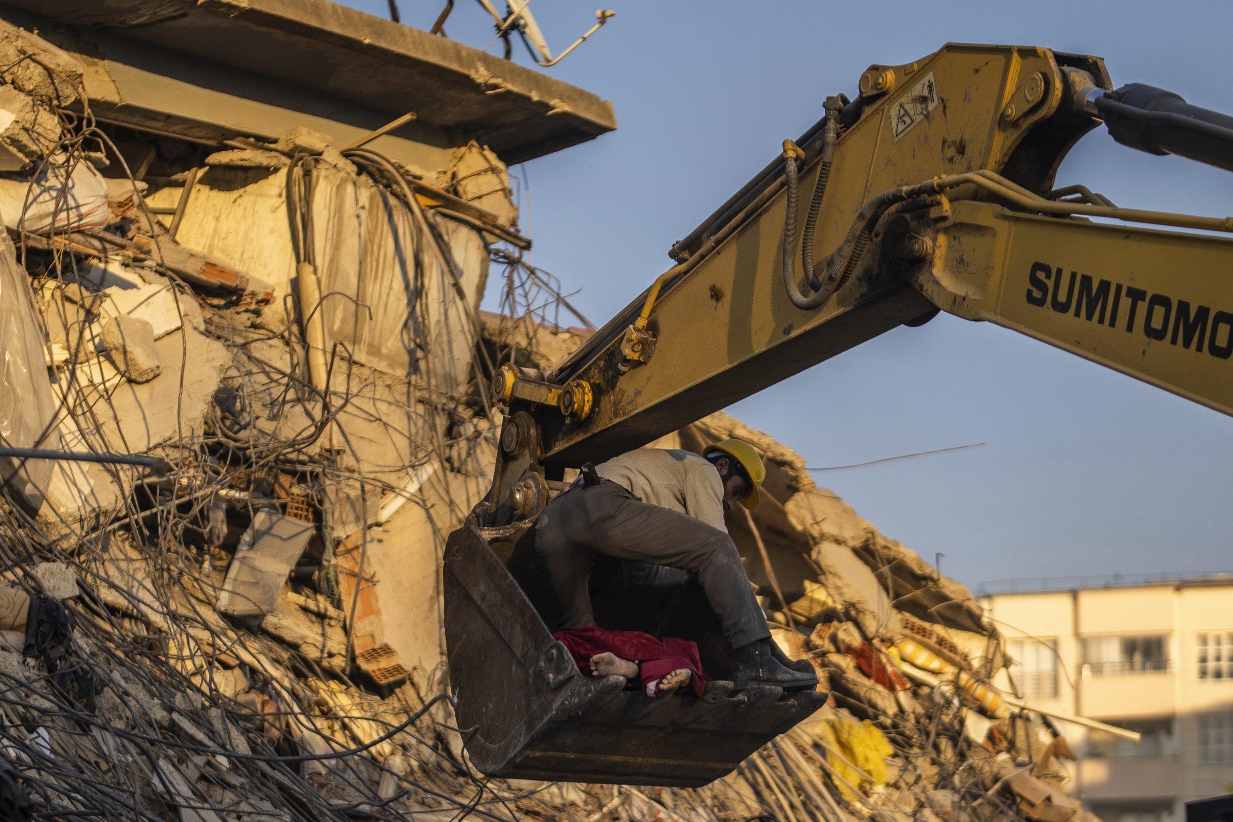  A man holds a dead body in the bucket of an excavator that is removing them from a building destroyed in a powerful earthquake in Kahramanmaras, Turkey, on Feb. 9, 2023. (AP Photo/Petros Giannakouris) 