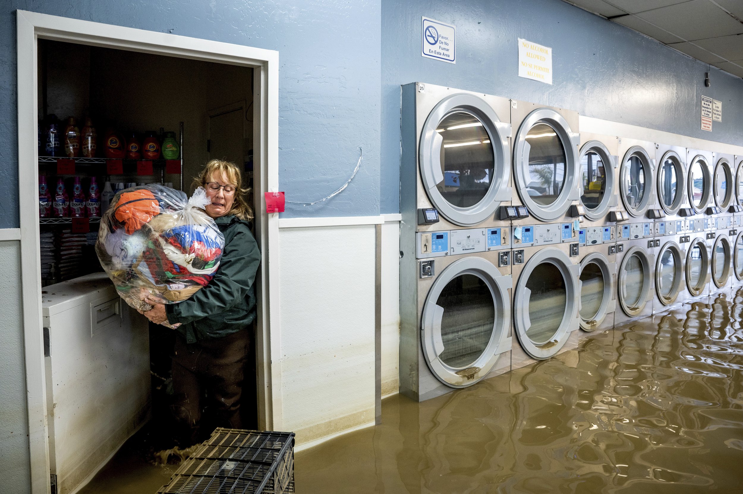  Pamela Cerruti carries clothing from Pajaro Coin Laundry in Pajaro, Calif., as floodwaters surround machines on March 14, 2023. "We lost it all. That's half a million dollars of equipment," said Pamela. (AP Photo/Noah Berger) 