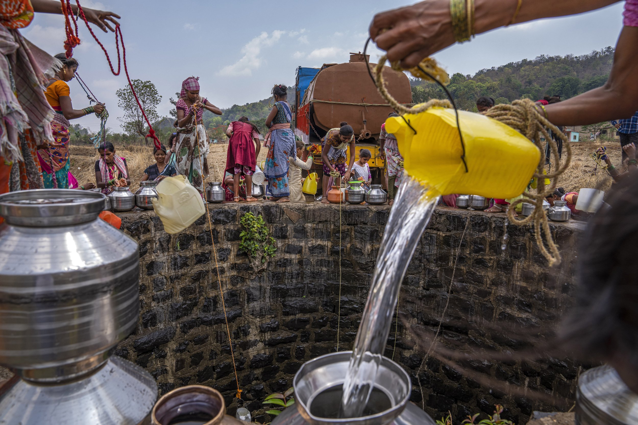  A villager pours water into a canister as others gather around a well to draw water in Telamwadi, northeast of Mumbai, India, on May 6, 2023. Tankers bring water from the Bhatsa River after it has been treated with chlorine. There have been protests