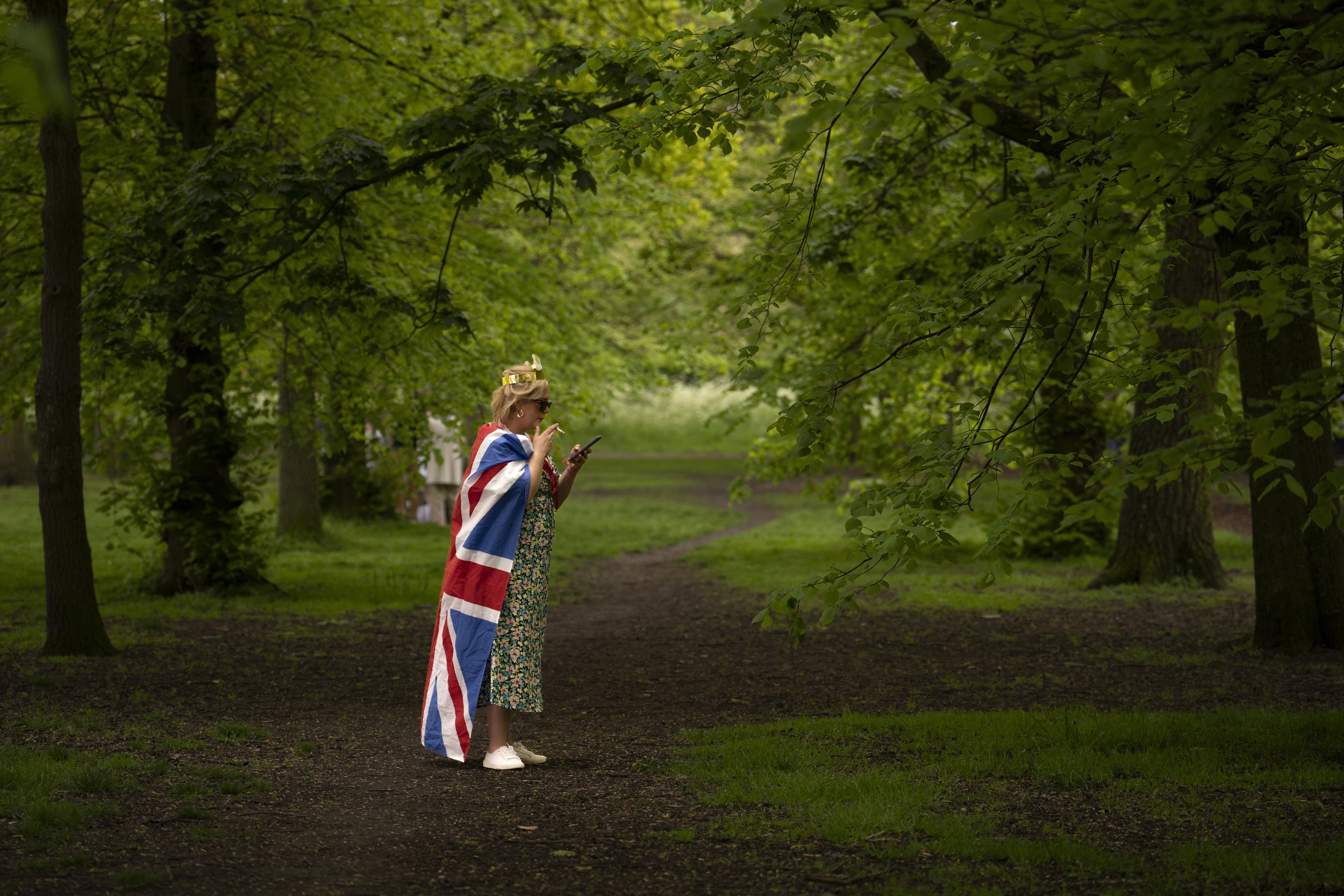  A woman draped in a British flag smokes during the Big Lunch celebrations in London Regent's Park, on May 7, 2023. The Big Lunch was part of the weekend of celebrations for the Coronation of King Charles III. (AP Photo/Vadim Ghirda) 