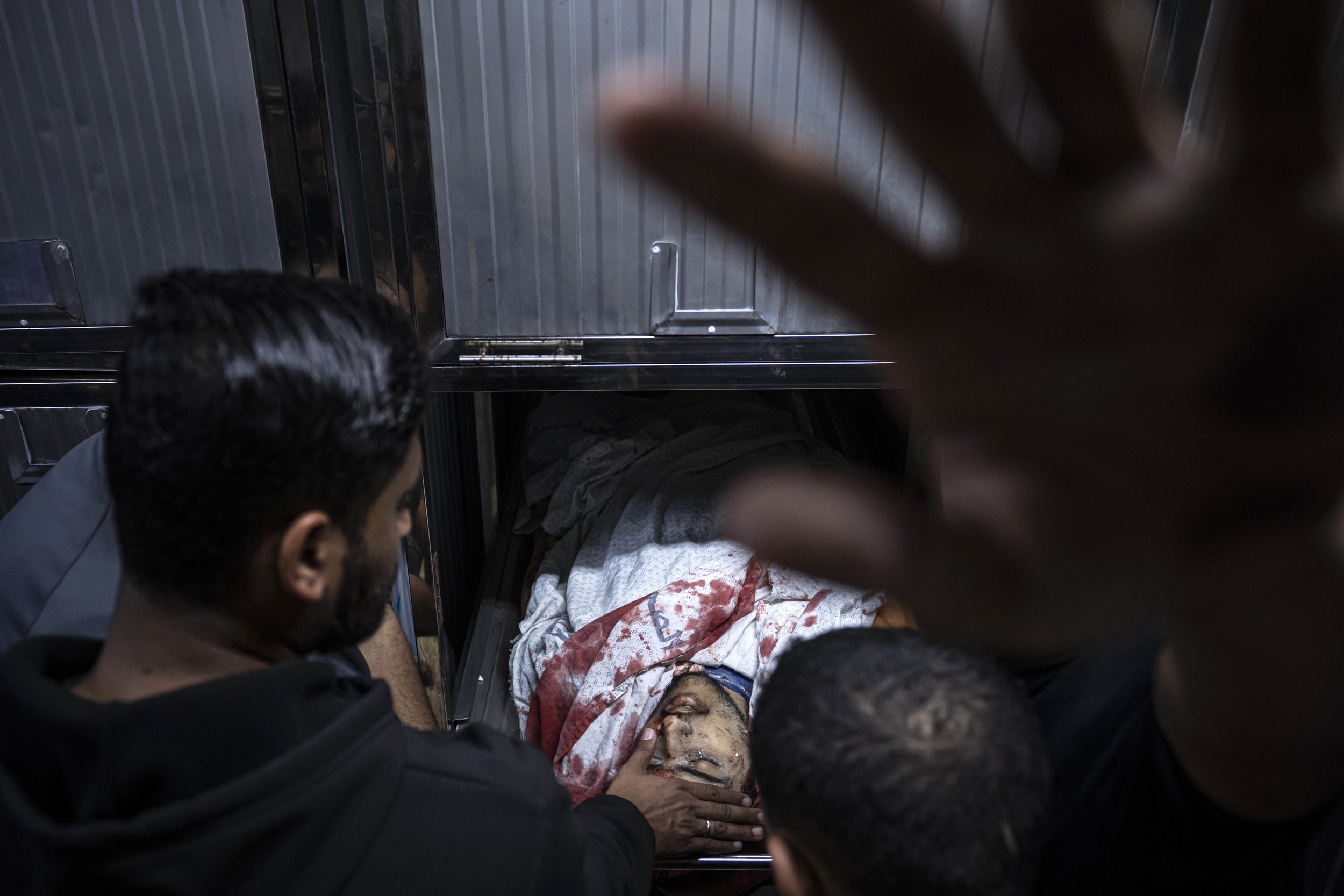  A mourner touches the body of a Palestinian man killed in an Israeli airstrike, in the morgue of Al-Shifa Hospital in Gaza City on May 9, 2023. The Israeli military said it killed three senior commanders of the militant Islamic Jihad group in target