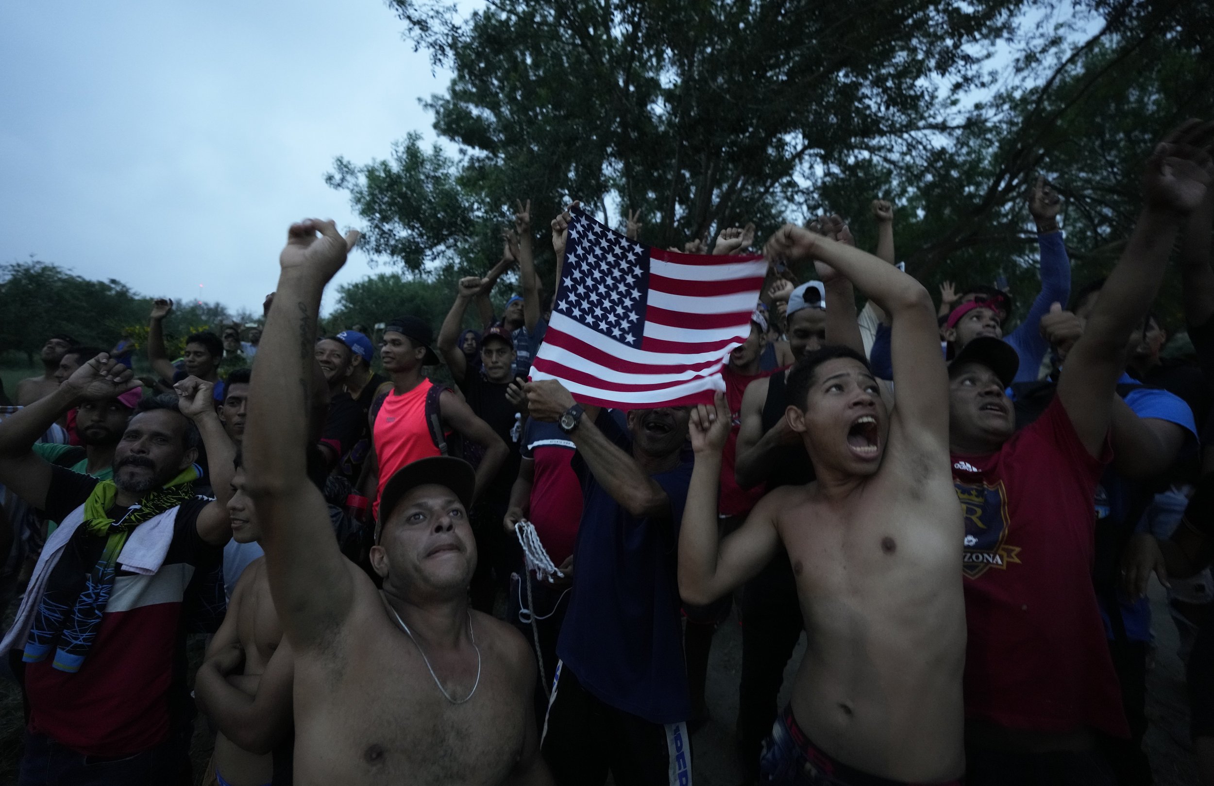  Venezuelan migrants wave a U.S. flag at a television helicopter flying over the Rio Grande in Matamoros, Mexico, on May 12, 2023, a day after pandemic-related asylum restrictions called Title 42 were lifted. (AP Photo/Fernando Llano) 