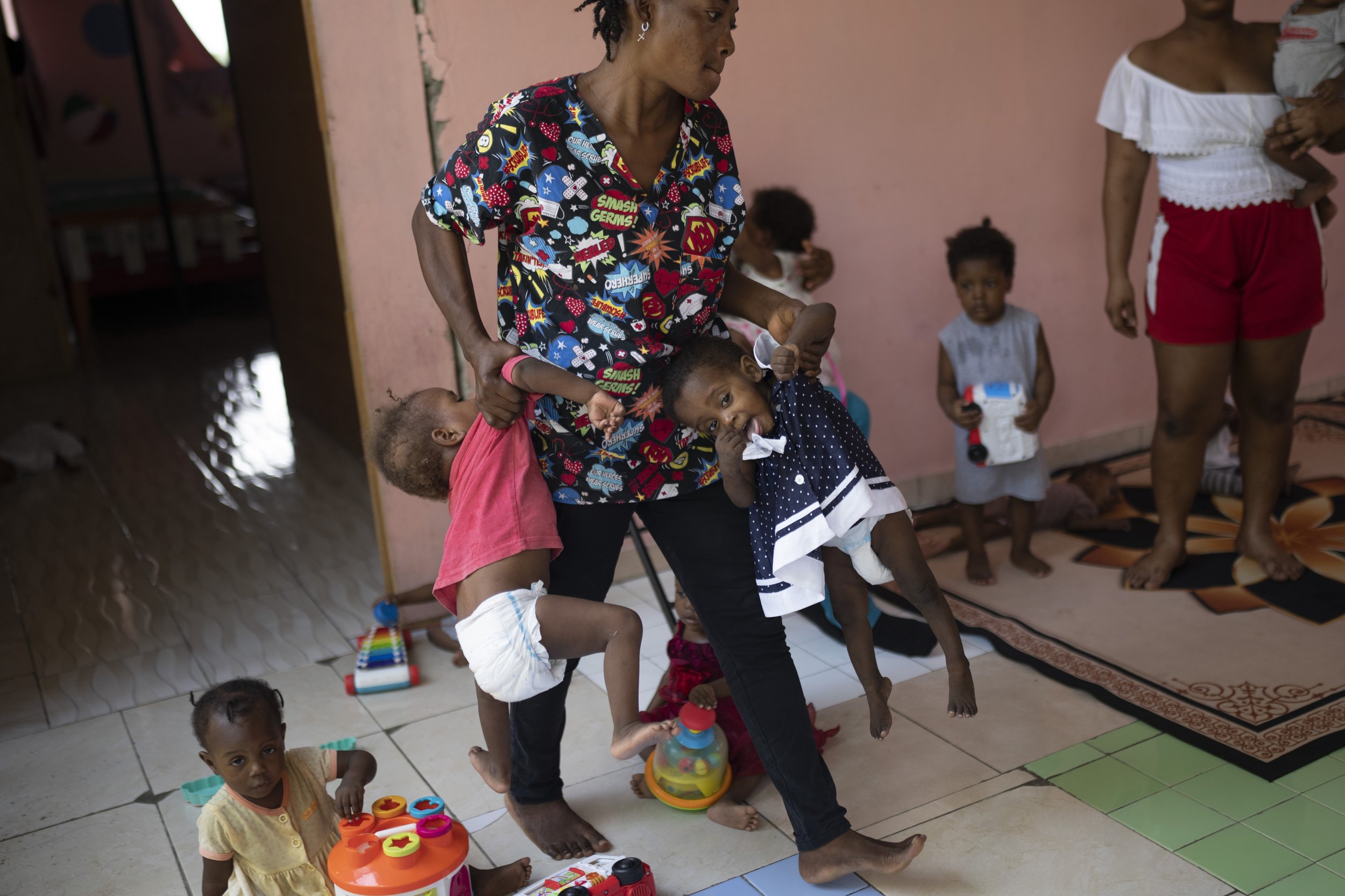  A woman carries two children as she takes care of them at Fontaine Hospital Center, which treats malnourished children in the Cite Soleil neighborhood of Port-au-Prince, Haiti, on May 29, 2023. (AP Photo/Ariana Cubillos) 