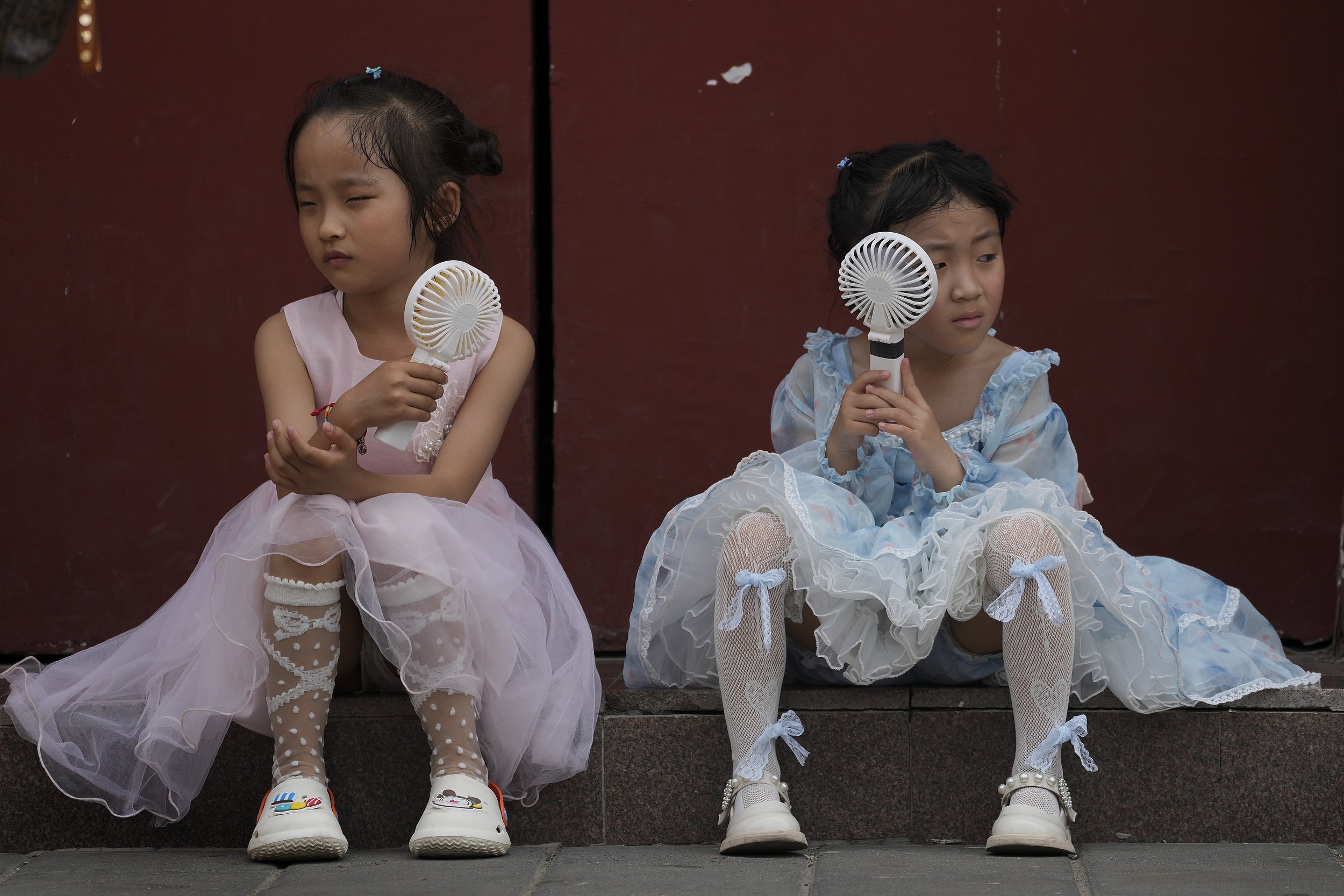  Children cool themselves with electric fans near the Forbidden City on a hot day in Beijing, on June 25, 2023. (AP Photo/Andy Wong) 