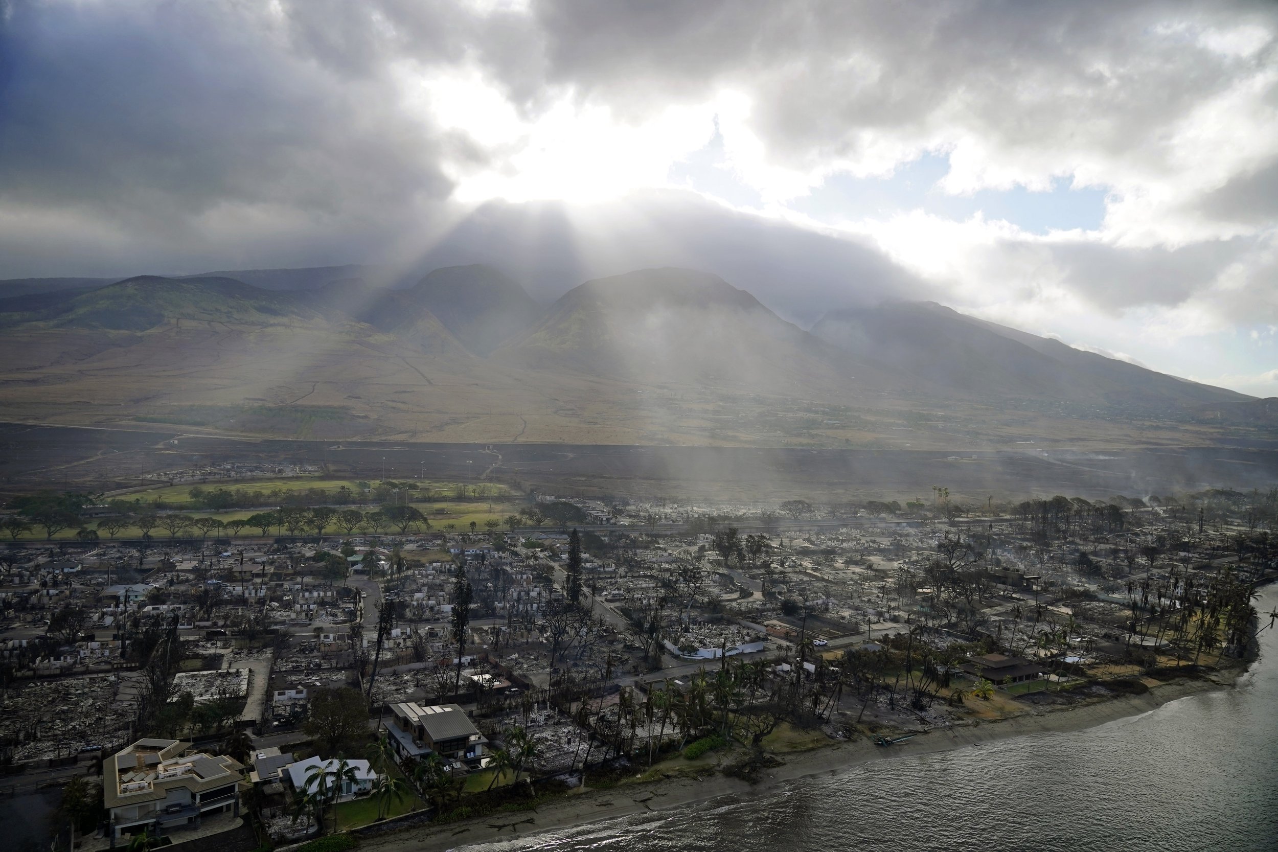  Sunlight bursts through a cloud over the wreckage of a wildfire in Lahaina, Hawaii, Aug. 10, 2023. (AP Photo/Rick Bowmer) 