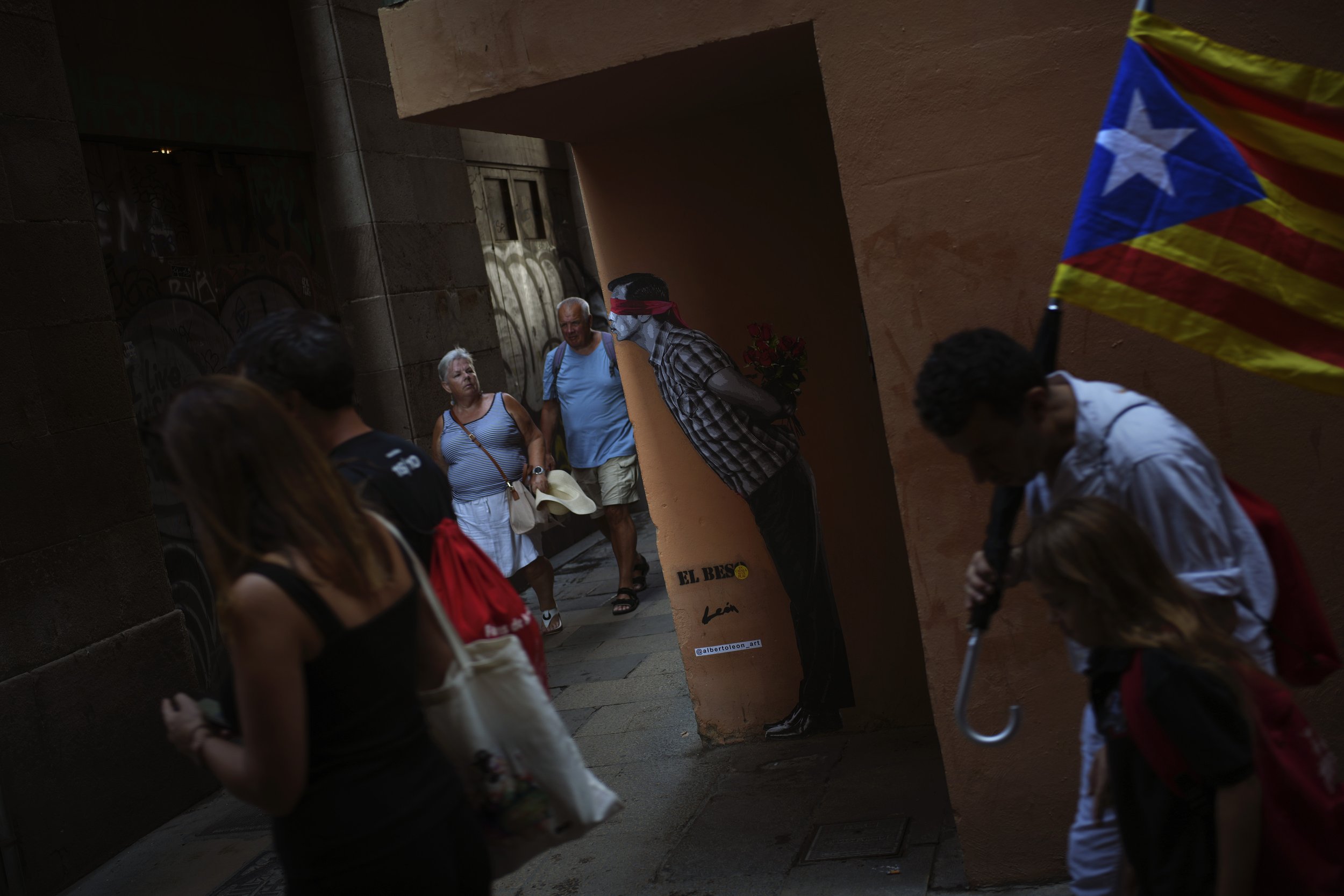  People, one of them carrying an esterada or independence flag, walk in downtown Barcelona, Spain, during the Catalan National Day on Sept. 11, 2023. (AP Photo/Emilio Morenatti) 