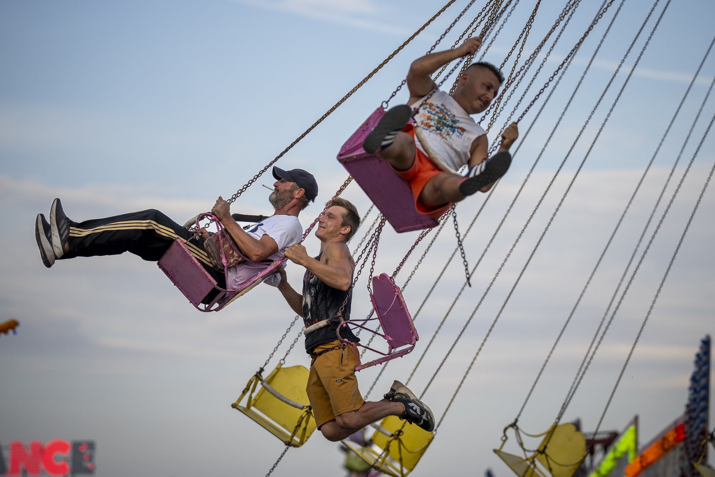  Men ride on a swing at a fair in Hagioaica, Romania, on Sept. 14, 2023. For many families in poorer areas of the country, Romania’s autumn fairs are one of the very few affordable entertainment events of the year. (AP Photo/Andreea Alexandru) 