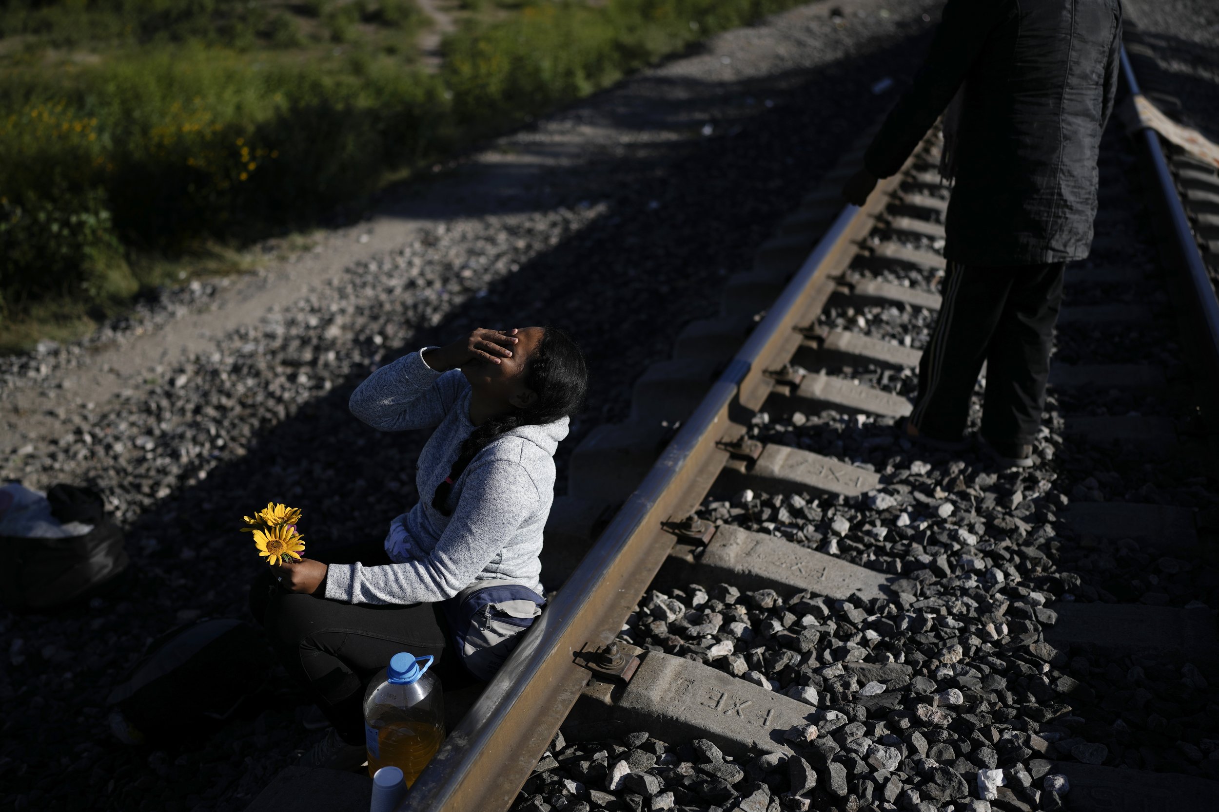  A Venezuelan migrant laughs as she jokes with her husband, who gave her a few flowers he picked in the grass, as they wait along the rail lines in hopes of boarding a freight train heading north in Huehuetoca, Mexico, on Sept. 20, 2023. (AP Photo/Ed