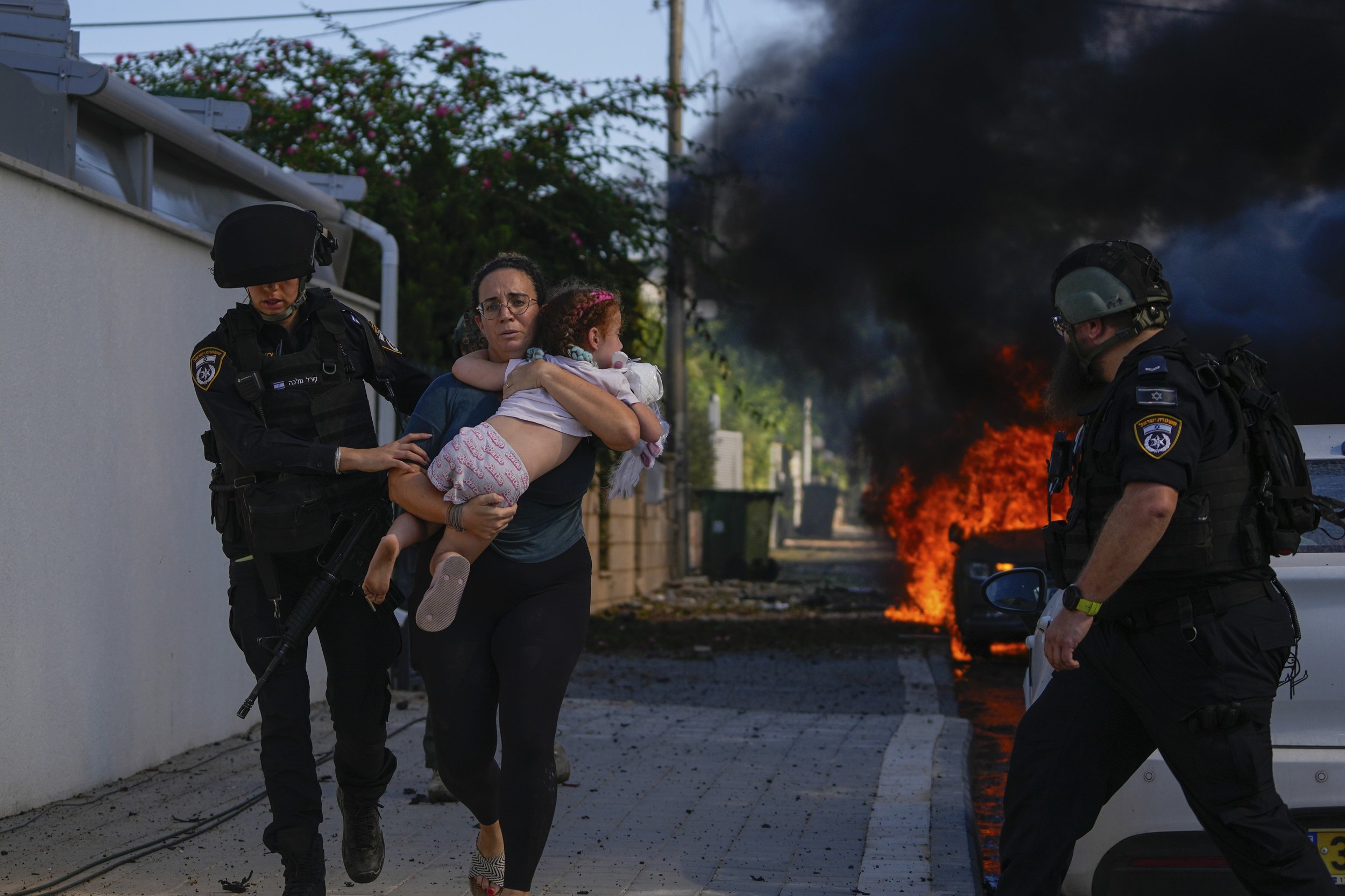  Police officers evacuate a woman and child in Ashkelon, Israel, from a site hit by a rocket fired from the Gaza Strip on Oct. 7, 2023. (AP Photo/Tsafrir Abayov) 