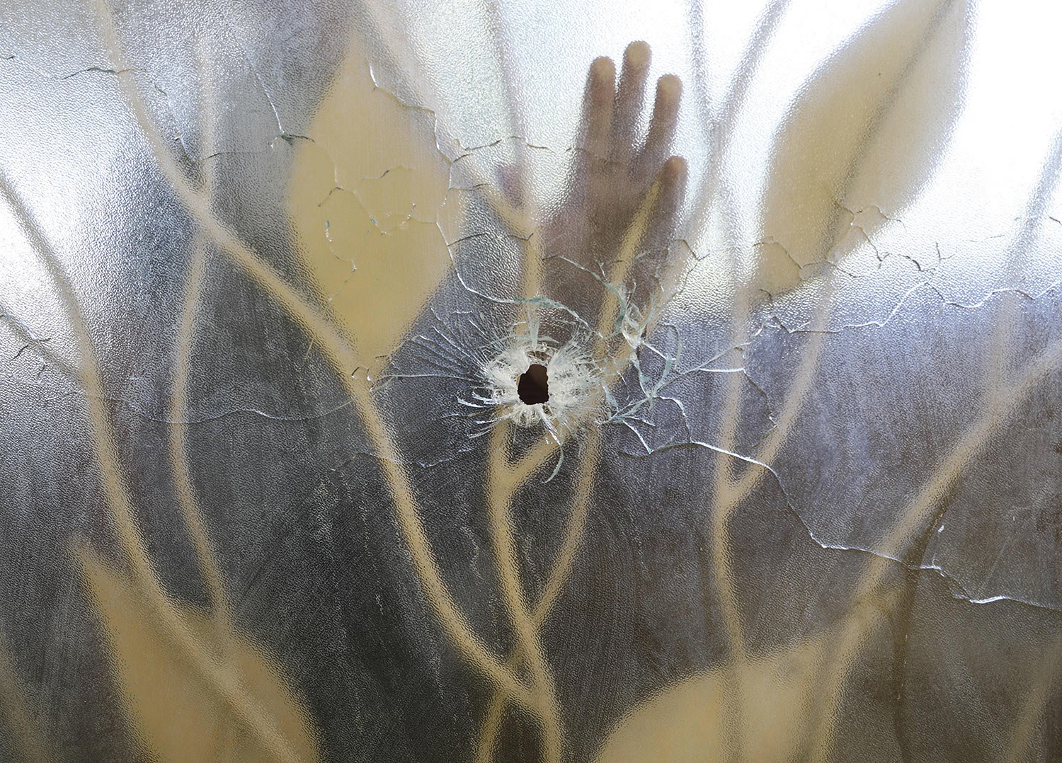  A hospital worker places his hand on a glass door within the clinic that was pierced by a bullet the previous day during an attack on the Fontaine Hospital Center in the Cité Soleil area of Port-au-Prince, Haiti, Nov. 16, 2023. (AP Photo/Odelyn Jose