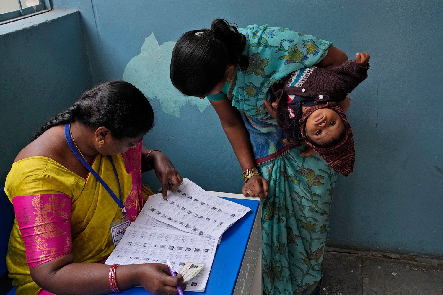  A woman checks for her name before casting her vote at a polling station during the Telangana state assembly elections in Hyderabad, India, Thursday, Nov. 30, 2023. (AP Photo/Mahesh Kumar A.) 