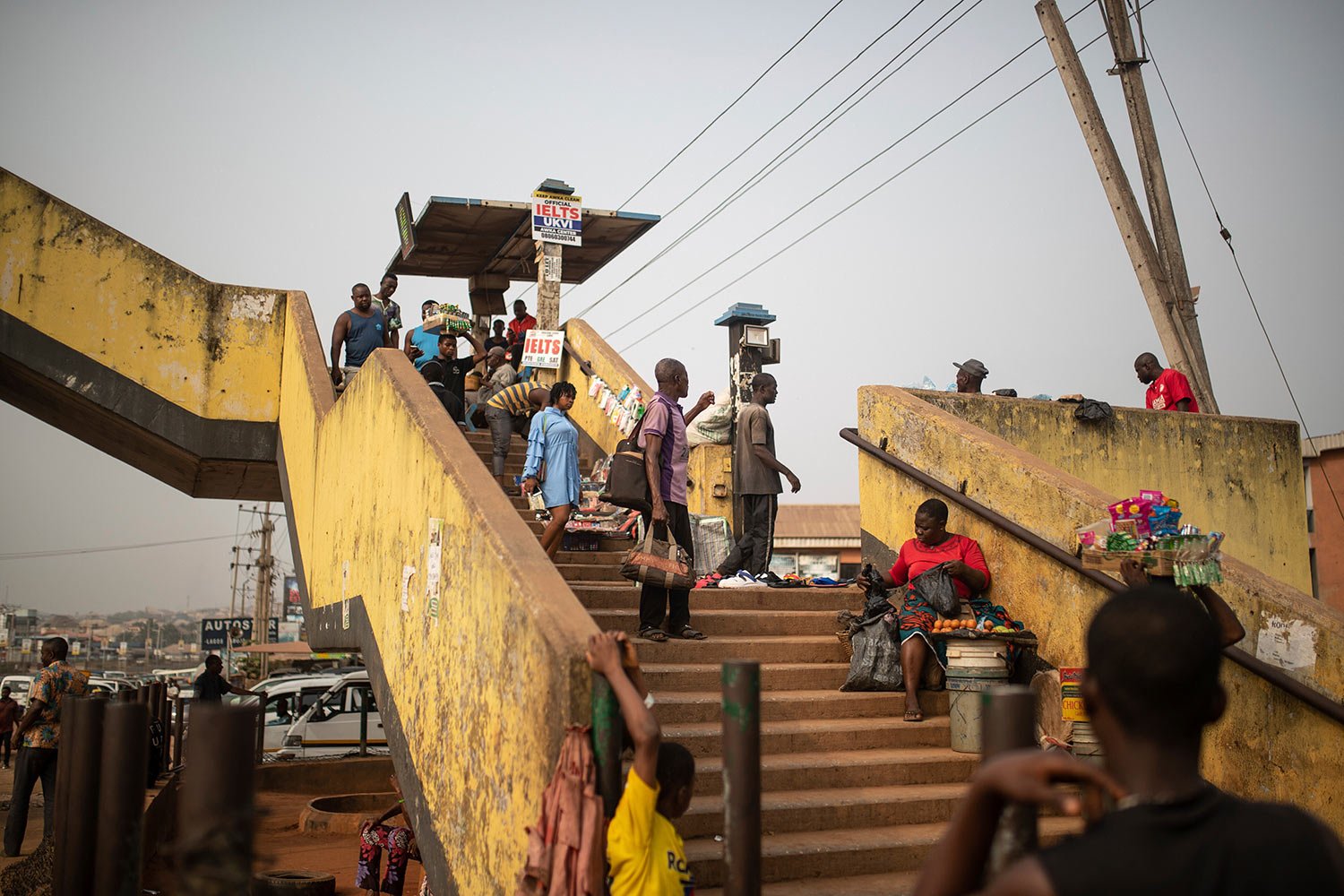  People cross a pedestrian bridge as street vendors sell their goods a day before Nigerian voters head to the polls to select a new president following the second and final term of incumbent President Muhammadu Buhari, in Anambra, Nigeria, Friday, Fe