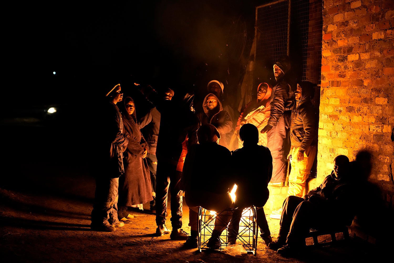  People huddle around a fire for warmth in the Angelo Informal Settlement in Boksburg, South Africa, on Thursday July 6, 2023. (AP Photo/Themba Hadebe) 