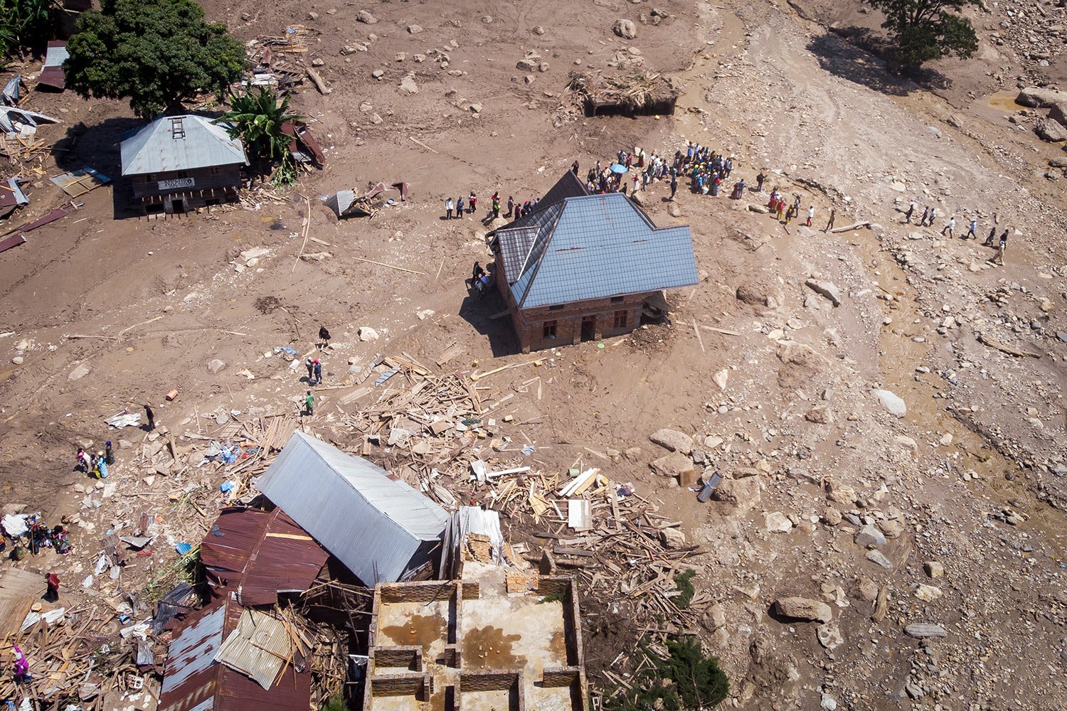  Survivors walk amidst debris next to destroyed buildings in the aftermath of floods in the village of Nyamukubi, South Kivu province, in Congo Monday, May 8, 2023. (AP Photo/Justin Kabumba) 