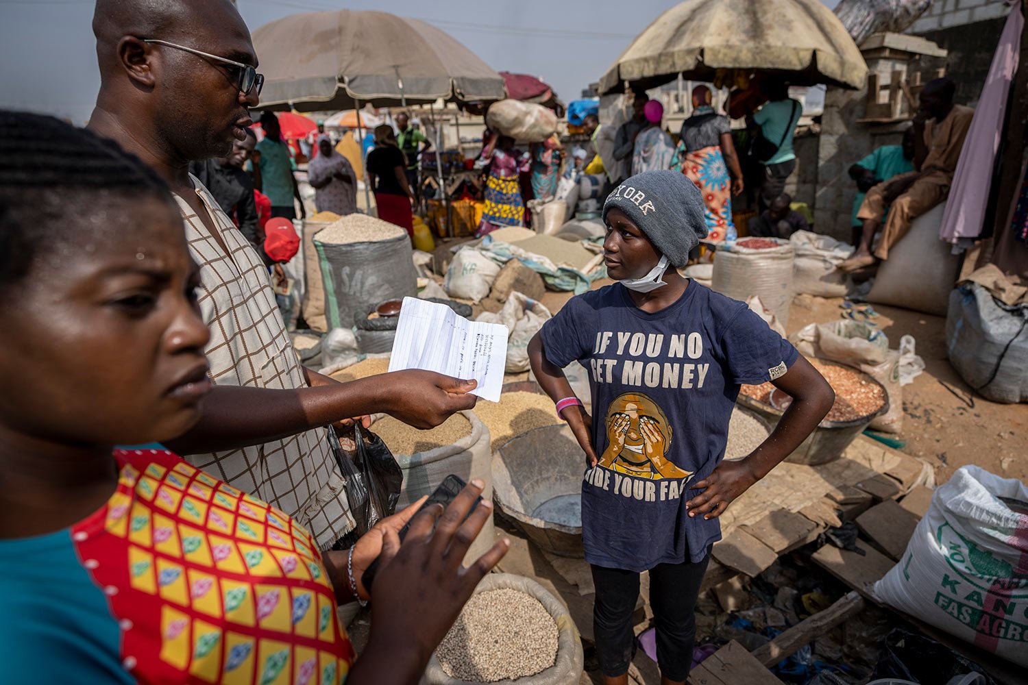  A customer buying a small bag of melon seeds discusses how he will send a bank transfer to the street seller, right, due to the crisis in the supply of banknotes, at the bi-weekly Karmo street market in Abuja, Nigeria Tuesday, Feb. 28, 2023. Writing