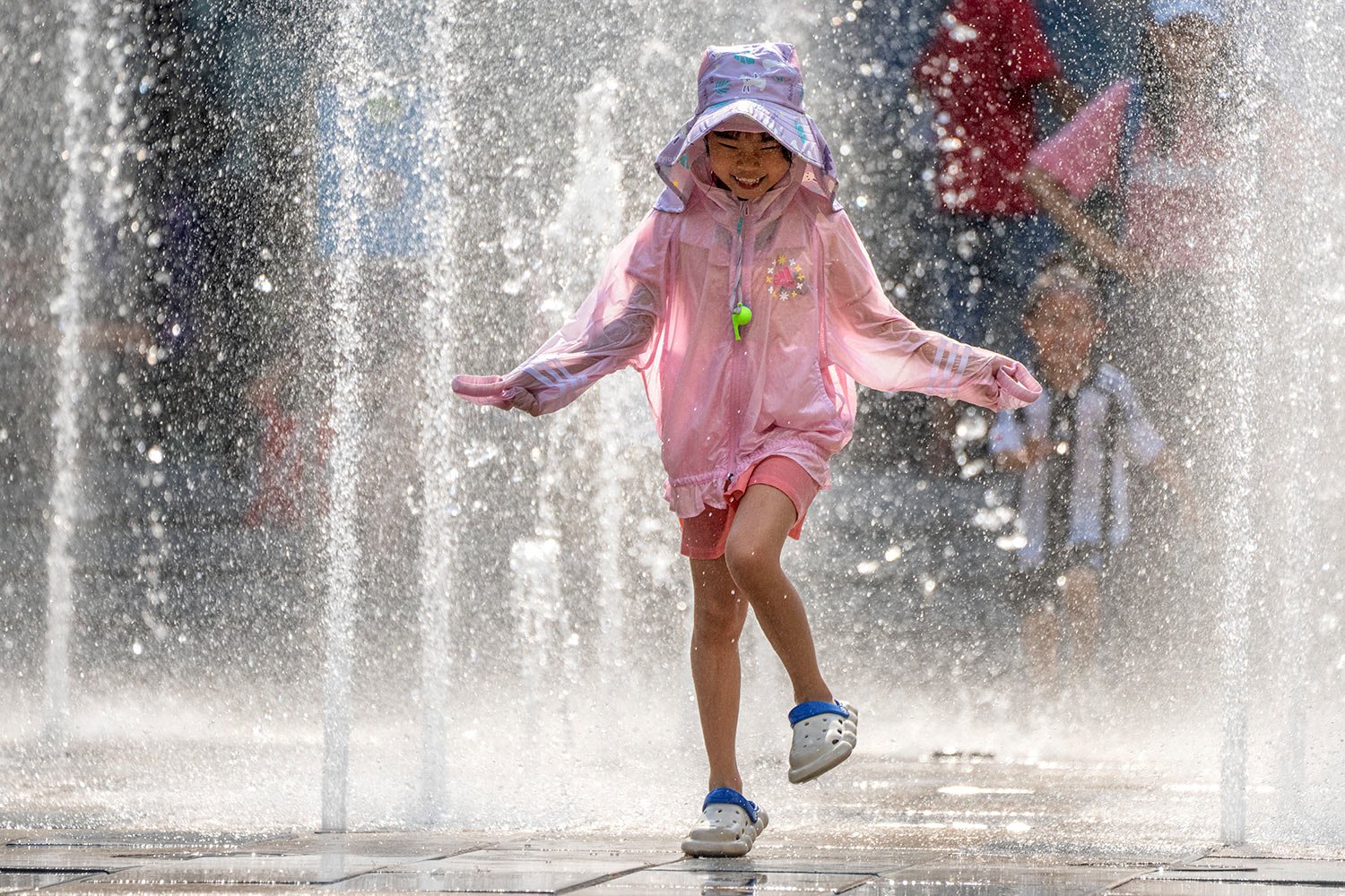  A girl runs as she plays in a fountain at a shopping mall in Beijing, Friday, June 23, 2023, as authorities issued a rare red alert for high temperatures in parts of China's capital.  (AP Photo/Mark Schiefelbein) 