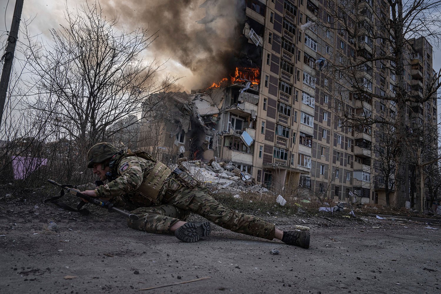  A Ukrainian police officer takes cover in front of a burning building that was hit in a Russian airstrike in Avdiivka, Ukraine, Friday, March 17, 2023. (AP Photo/Evgeniy Maloletka) 