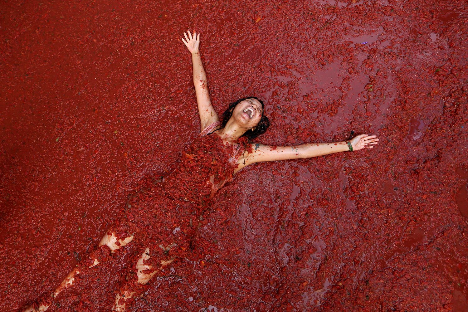  A woman reacts during the annual tomato fight fiesta called "Tomatina" in the village of Bunol near Valencia, Spain, Wednesday, Aug. 30, 2023. (AP Photo/Alberto Saiz) 