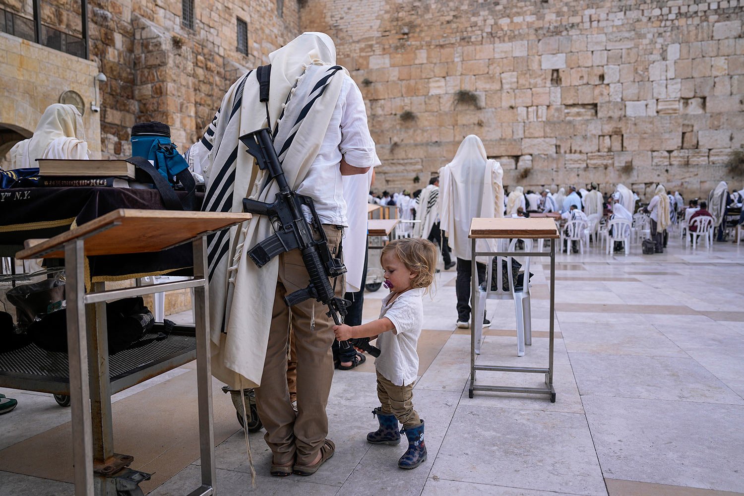  An off-duty member of Israel's security forces joins worshippers at the Western Wall, the holiest site where Jews can pray, in the Old City of Jerusalem, Tuesday, Nov. 14, 2023. (AP Photo/Ohad Zwigenberg) 