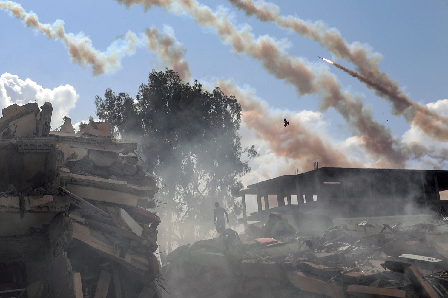  Rockets are fired from the Gaza Strip toward Israel over destroyed buildings following Israeli airstrikes on Gaza City, central Gaza Strip, Thursday, Oct. 19, 2023. (AP Photo/Mohammed Dahman) 