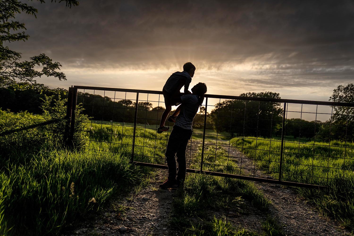  The sun sets as Meredith Ellis looks at cattle with her son, GC, 6, on their ranch in Rosston, Texas, Thursday, April 20, 2023. Ellis has seen how global warming is altering her land. She calls it an “existential crisis,” the backdrop to the endless
