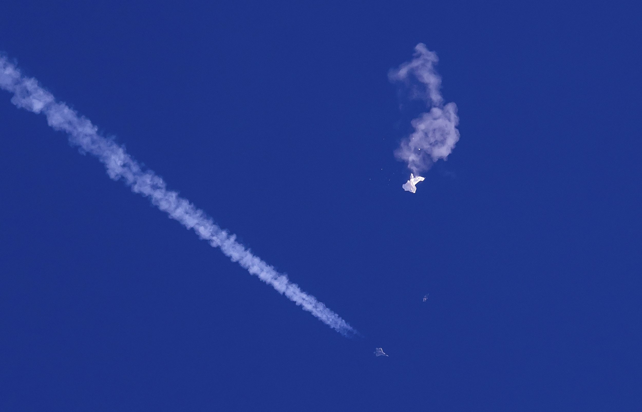  A fighter jet flies past the remnants of a large balloon after it was shot down above the Atlantic Ocean, just off the coast of Myrtle Beach, S.C., on Feb. 4, 2023. The Chinese balloon was part of a large surveillance program that China has been con