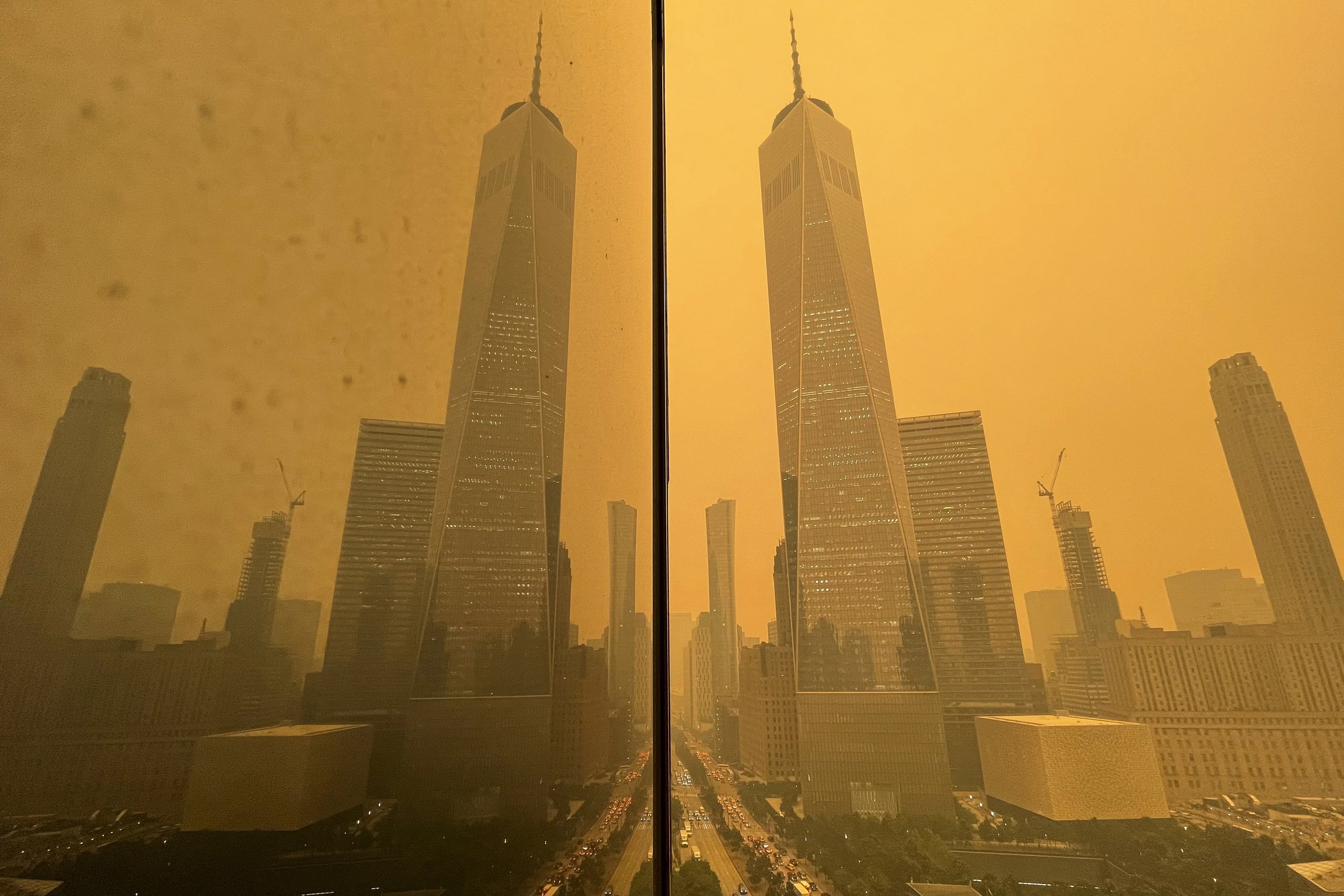  Traffic in New York moves along West Street past One World Trade Center, in this mirror image reflected in the facade of a building on June 7, 2023. The smokey haze was caused by wildfires in Canada. (AP Photo/Andy Bao) 