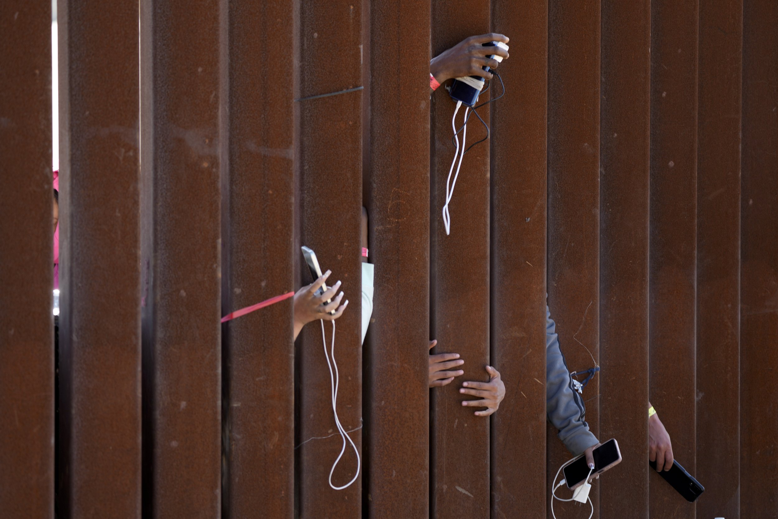  Migrants waiting to apply for asylum between two border walls hold out phones in hopes of getting a charge on May 11, 2023, in San Diego. Pandemic-related U.S. asylum restrictions, known as Title 42, expired on May 11. (AP Photo/Gregory Bull) 