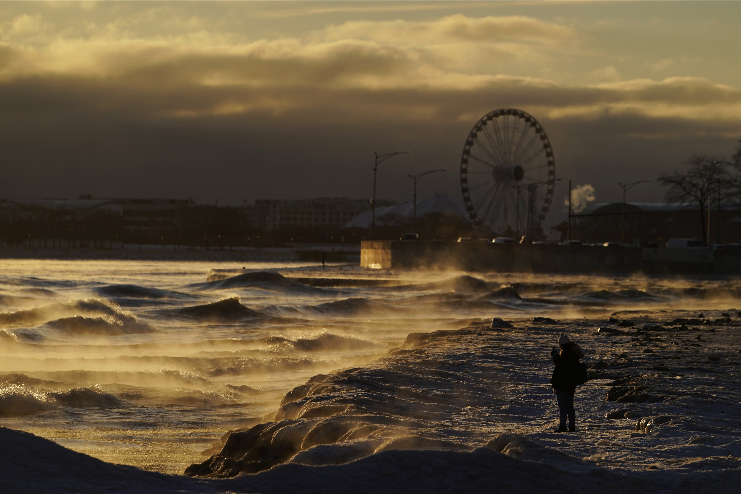  A person takes a picture of the waves crashing on to the shore as ice forms on Oak Street Beach in Chicago on Feb. 3, 2023. (AP Photo/Kiichiro Sato) 