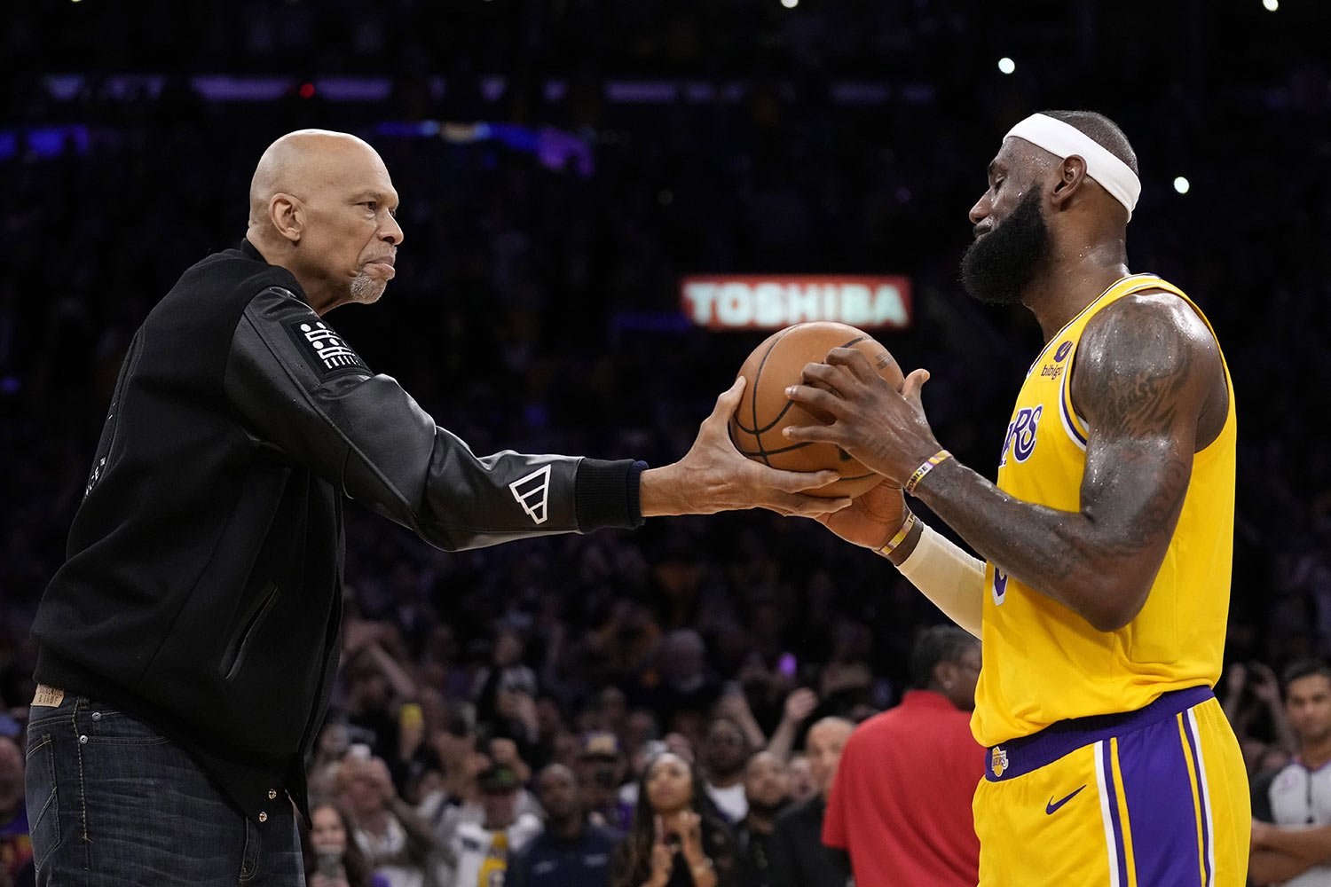  Kareem Abdul-Jabbar, left, hands the ball to Los Angeles Lakers forward LeBron James after passing Abdul-Jabbar to become the NBA's all-time leading scorer during the second half of an NBA basketball game against the Oklahoma City Thunder, in Los An