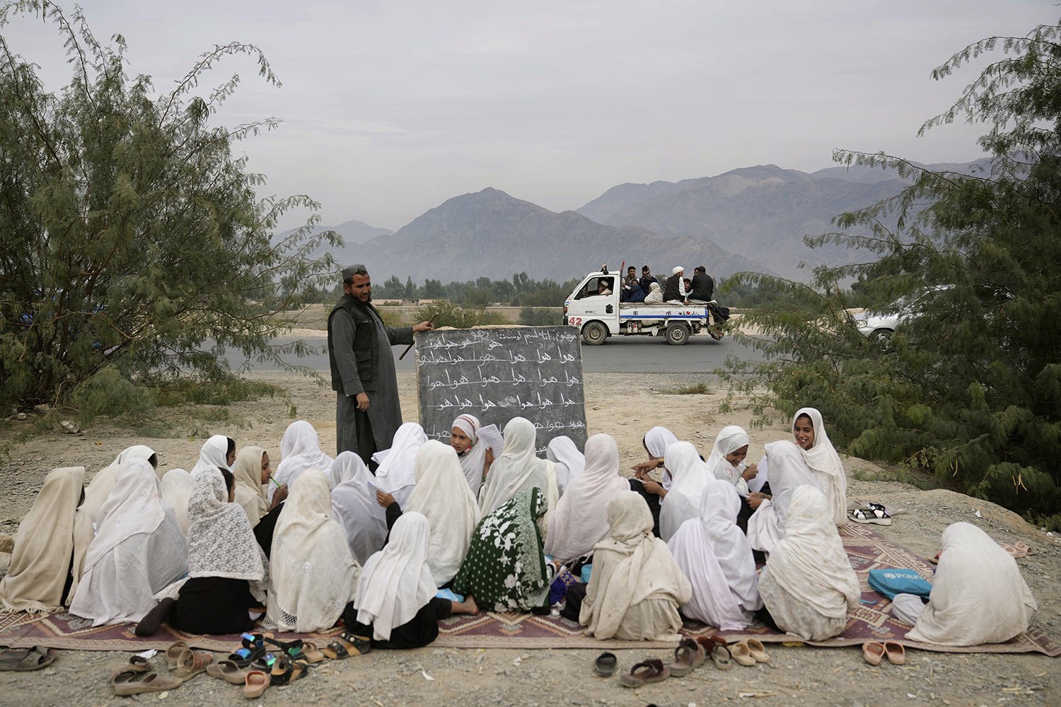  Afghan refugees pass by an outdoor girls classroom in Torkham, Afghanistan, Nov. 18, 2023.  (AP Photo/Ebrahim Noroozi) 