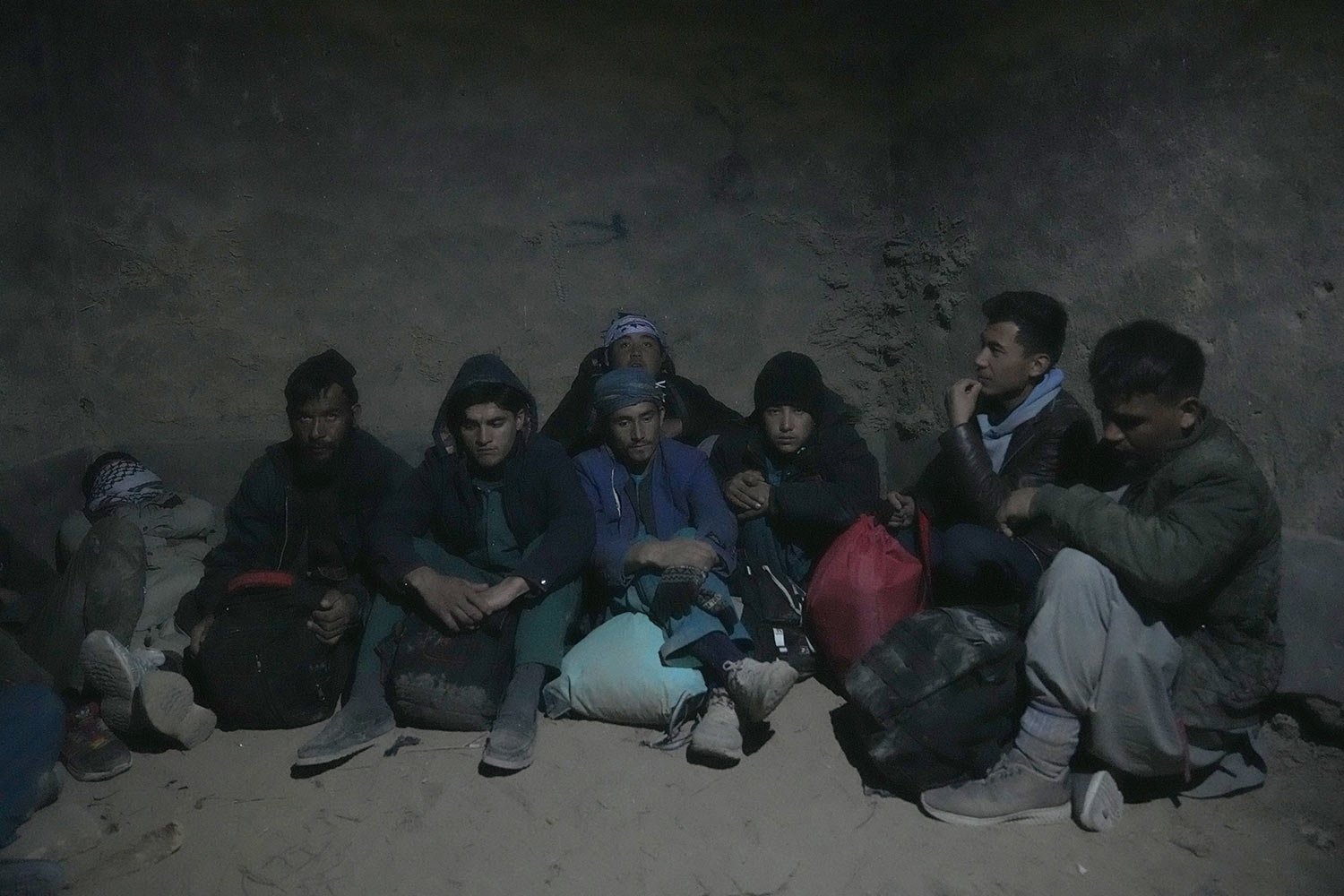  Young Shiite Afghan immigrants wait for midnight in ruins in the desert around the city of Zaranj, Afghanistan, near the the Iran-Afghanistan border wall, to try to cross over the Iranian border wall into Iran, Dec. 25, 2023. (AP Photo/Ebrahim Noroo