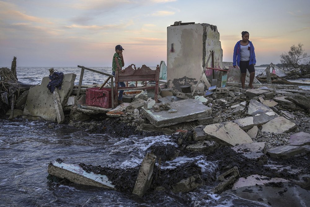  Yahir Mayoral and Emily Camacho walk amid the rubble of their grandmother's home, destroyed by flooding driven by a sea-level rise in their coastal community of El Bosque, in the state of Tabasco, Mexico, Nov. 30, 2023. (AP Photo/Felix Marquez) 