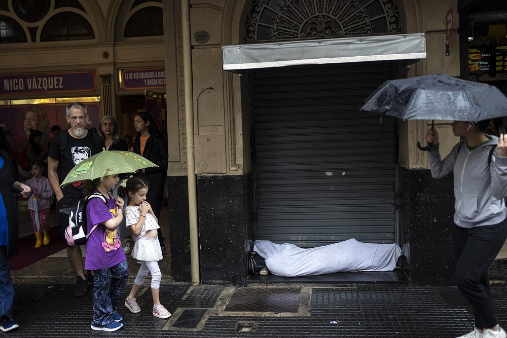  People walk past a homeless person in downtown Buenos Aires, Argentina, Dec. 6, 2023. The poverty level in Argentina reached 44.7% in the third quarter of 2023, according to a report by the Argentine Catholic University. (AP Photo/Rodrigo Abd) 