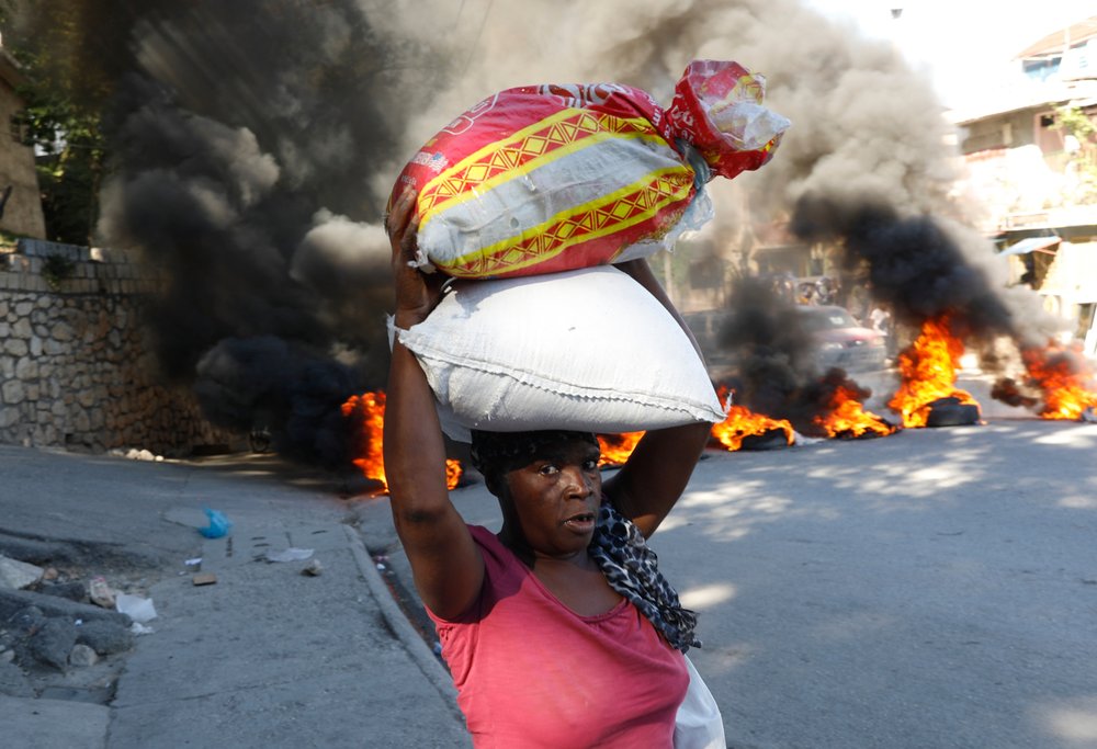  A woman walks past burning tires set on fire by protesters to call attention to the country's insecurity and demanding the resignation of the prime minister in Port-au-Prince, Haiti, Jan. 18, 2024. (AP Photo/Odelyn Joseph) 
