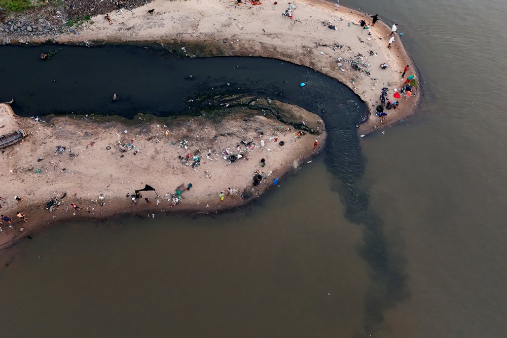  People fish next to drainage that flows into the Paraguay River in Asuncion, Paraguay, Jan. 28, 2024. (AP Photo/Jorge Saenz) 