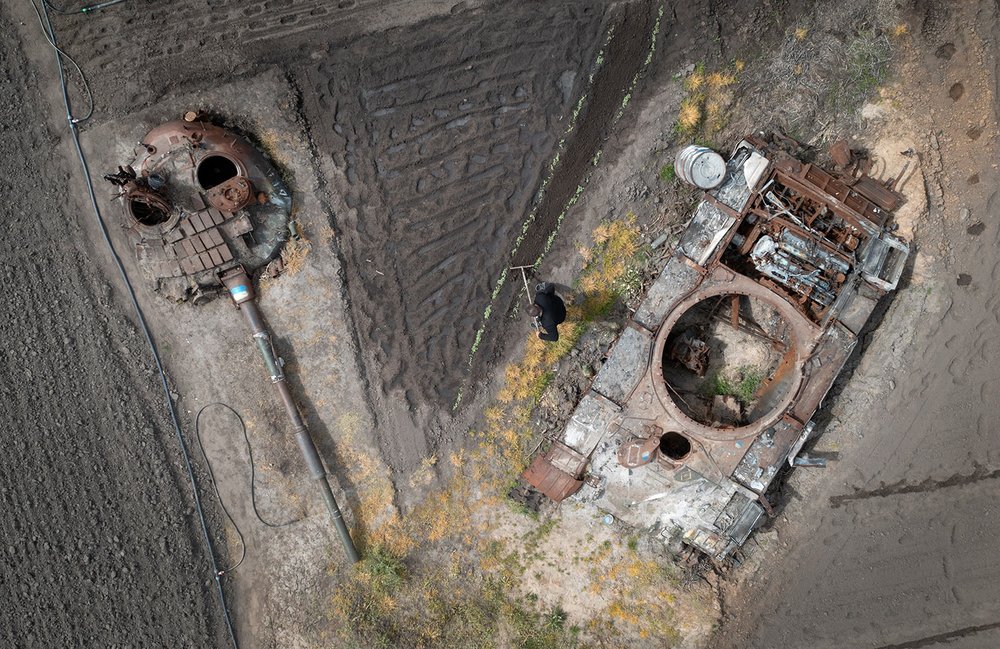  A man plants sunflowers in his garden between a damaged Russian tank and its turret in the village of Velyka Dymerka, Ukraine, Wednesday, May 17, 2023. (AP Photo/Efrem Lukatsky) 