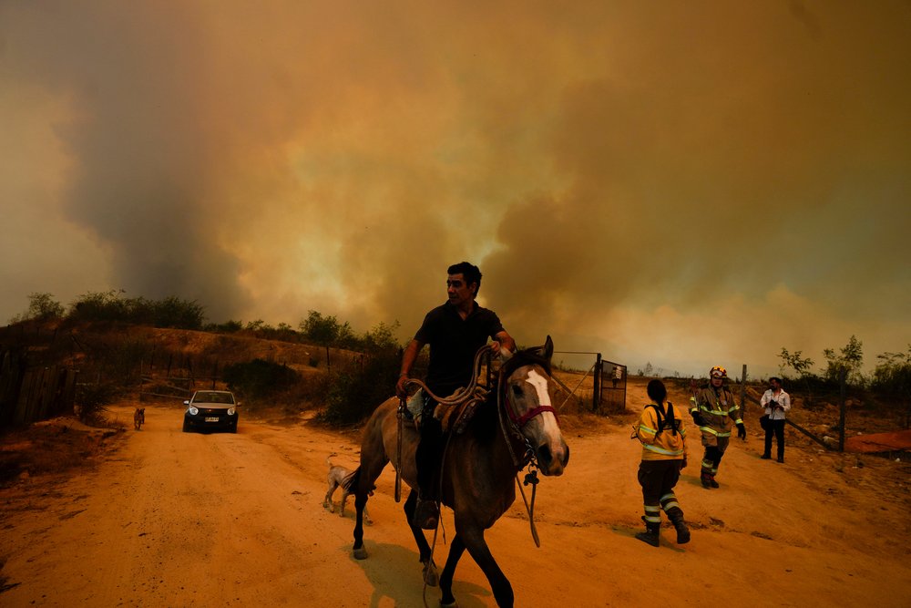  A resident flees an encroaching forest fire in Vina del Mar, Chile, Saturday, Feb. 3, 2024. (AP Photo/ Esteban Felix) 