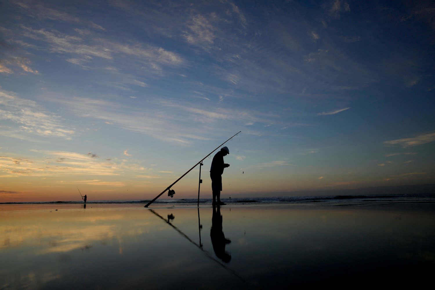  A fisherman prepares his rod on the shore of the South Atlantic Ocean in Monte Hermoso, Argentina, Wednesday, Feb. 21, 2024. (AP Photo/Natacha Pisarenko) 