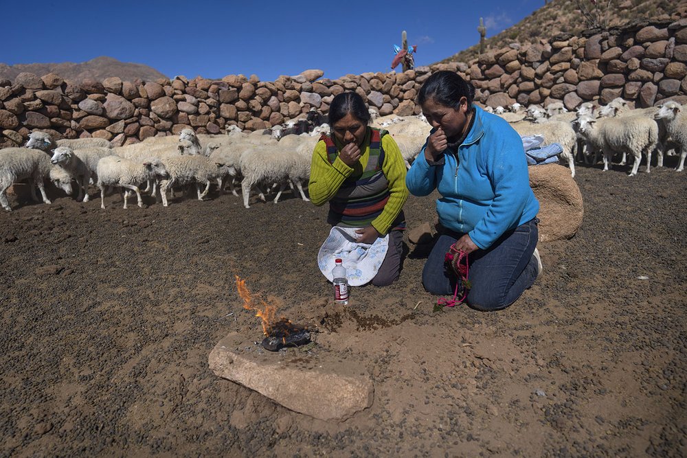   Vilma Callata, 45, left, make an offering to the earth with her sister while they take care of their animals in Tusaquillas, Jujuy Province, Argentina April 23, 2023.  
