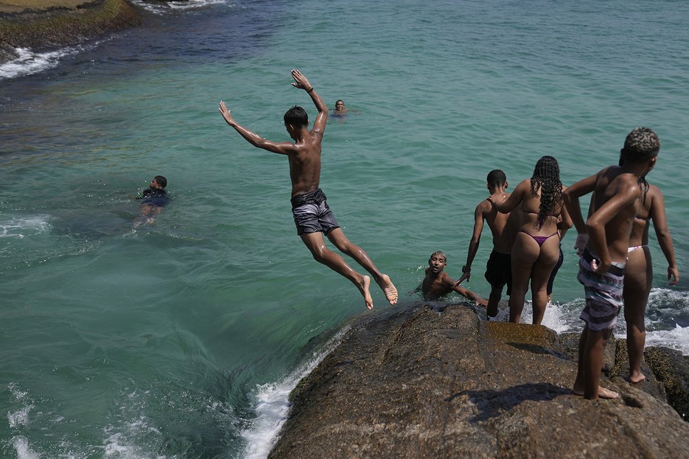  A youth leaps off the edge of a rock into the waters of Arpoador beach amid a heat wave, in Rio de Janeiro, Brazil, March 20, 2024. (AP Photo/Silvia Izquierdo) 