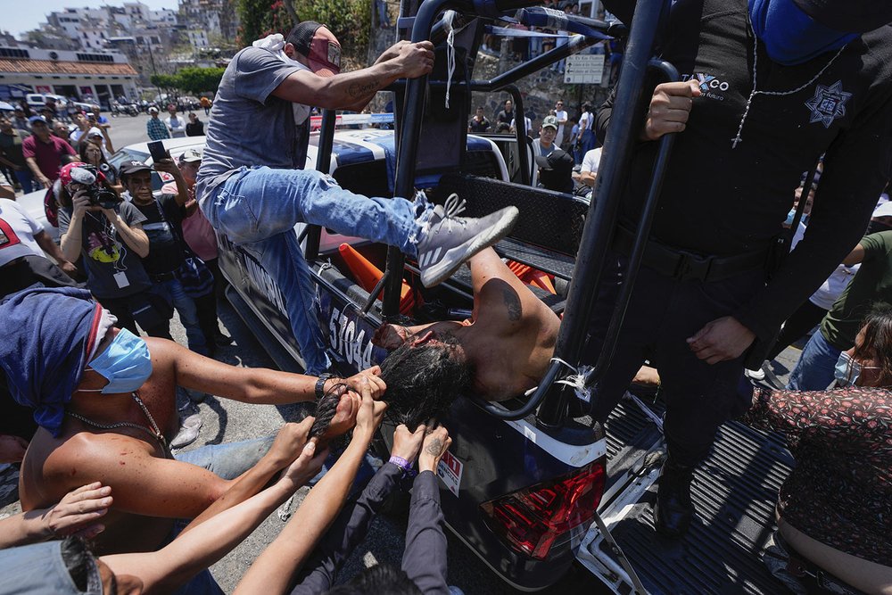  A woman suspected in the kidnapping and killing of an 8-year-old girl, is dragged out of a police vehicle by a mob in Taxco, Mexico, March 28, 2024. Police then picked her up off the ground and took her away. The Guerrero state prosecutors’ office l