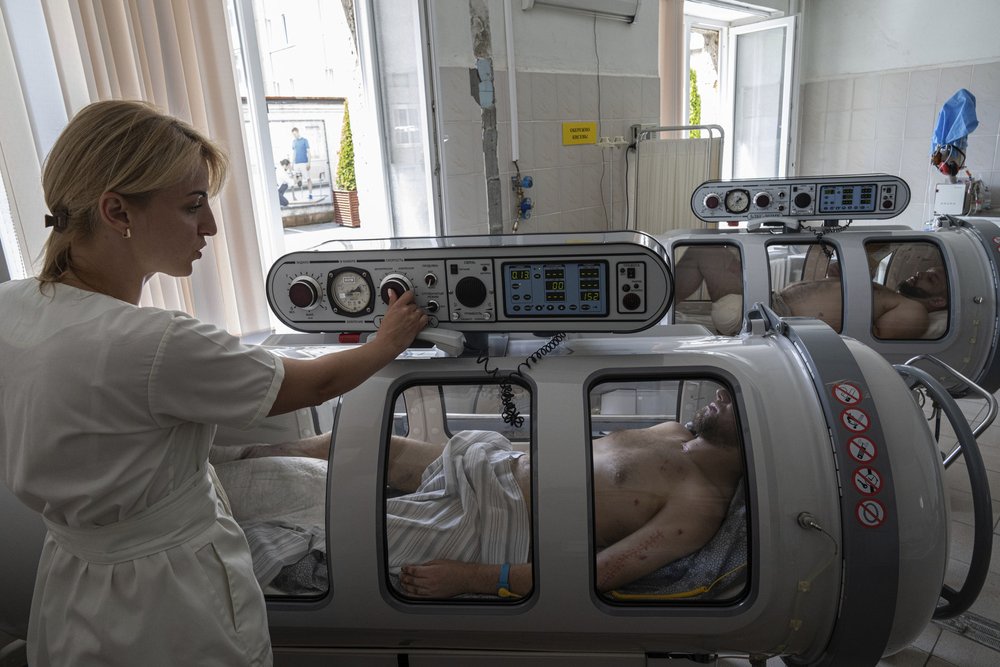  An anaesthesiologist sets up a hyperbaric chamber for Vitaliy Bilyak, a Ukrainian serviceman, during his treatment at St. Panteleimon hospital in Lviv, Ukraine, Tuesday, July 25, 2023.  