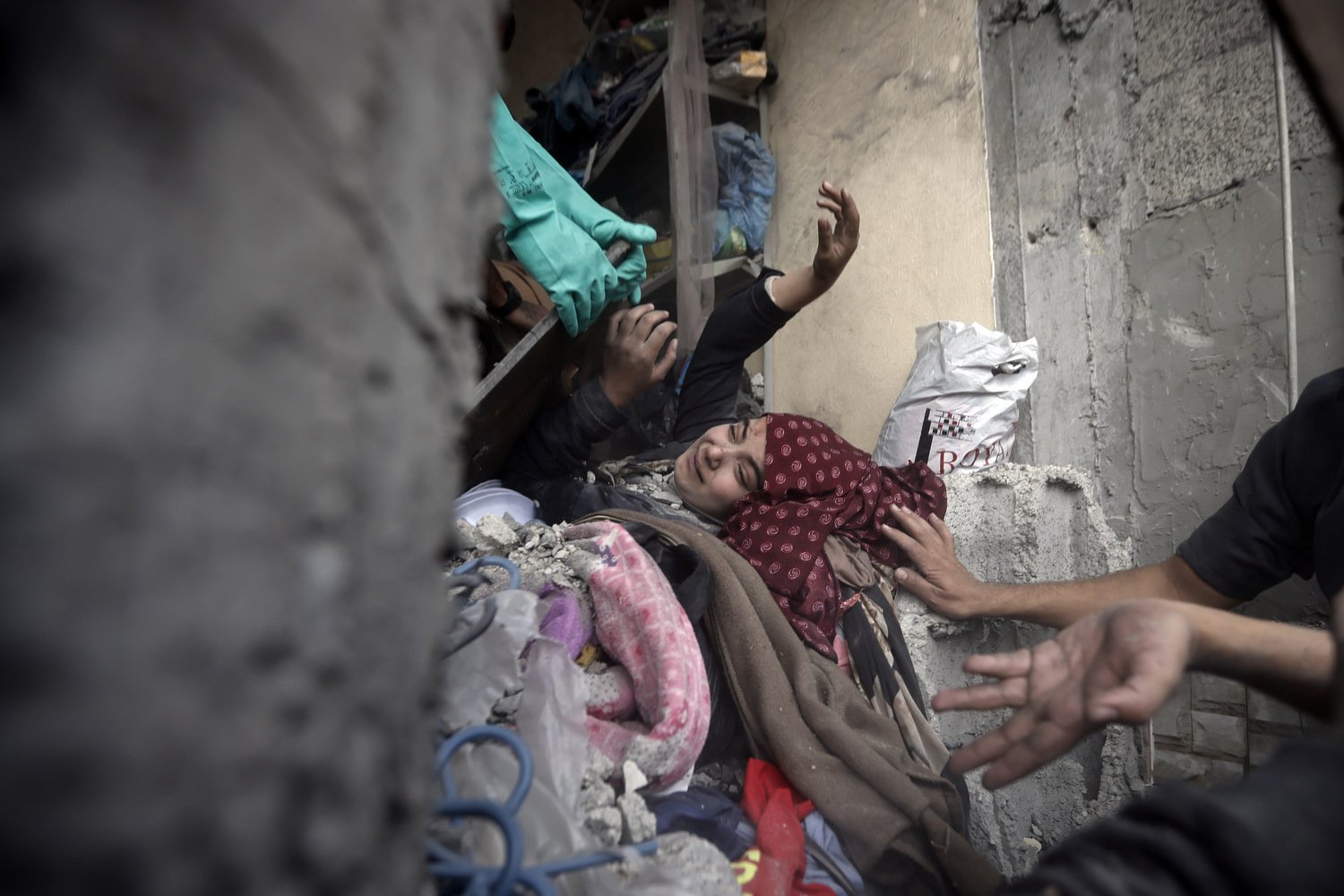  Palestinians try to rescue a woman stuck under the rubble of a destroyed building following Israeli airstrikes in Khan Younis refugee camp, southern Gaza Strip, Thursday, Dec. 7, 2023.  