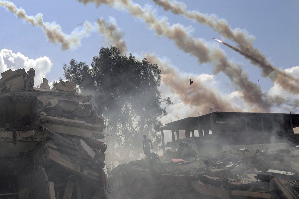  Rockets are fired from the Gaza Strip toward Israel over destroyed buildings following Israeli airstrikes on Gaza City on Oct. 19, 2023.  